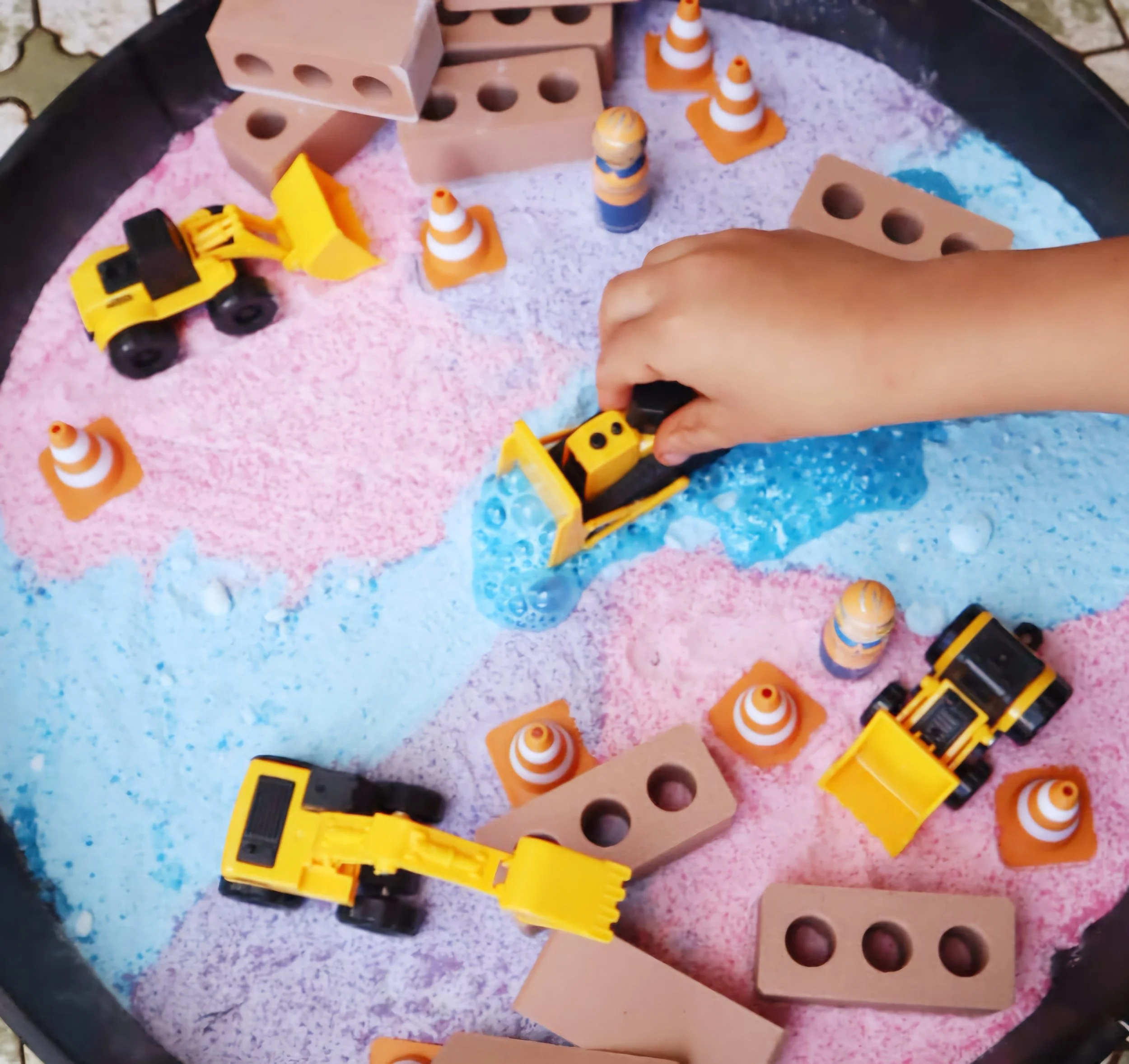 Hands-on construction play setup with mini bricks, traffic cones and construction vehicles.