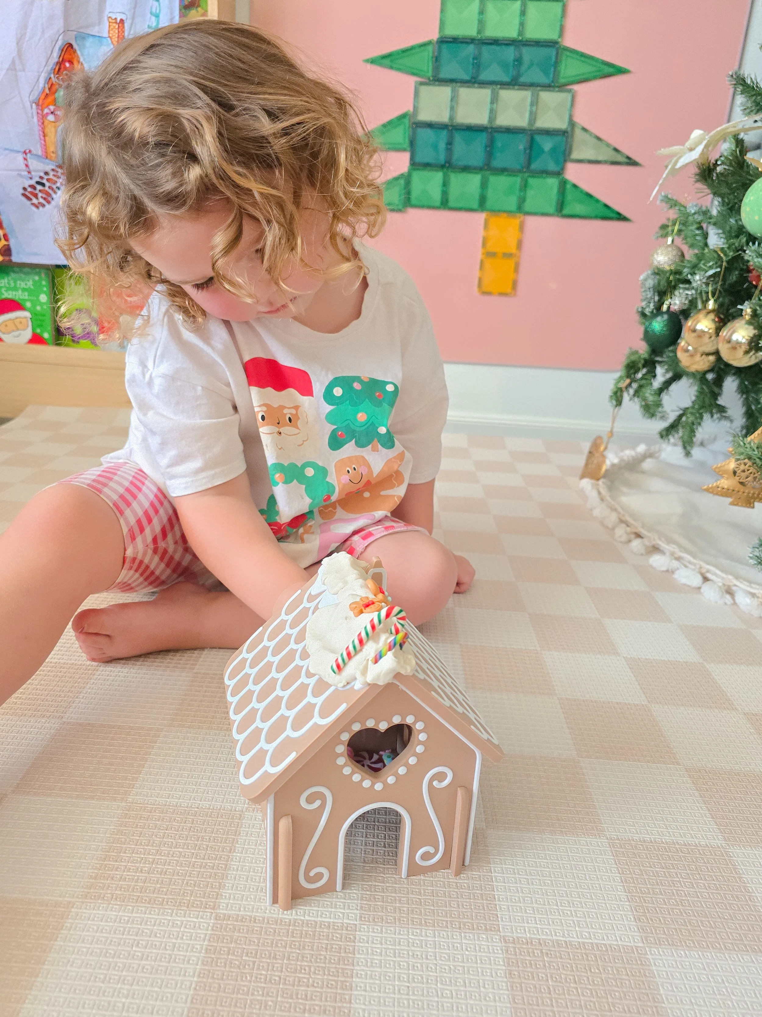 childs decorating reuseable gingerbread house with playdough and candy