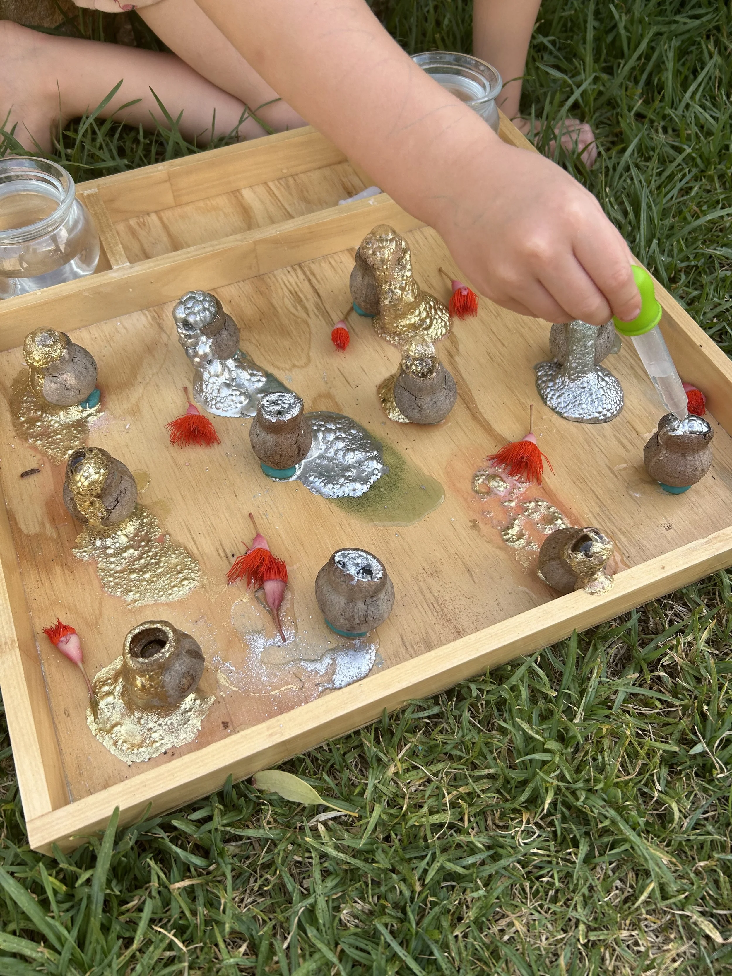 Child creating colourful potion reactions during a NAIDOC Week inspired sensory play activity using natural elements and hands-on exploration.