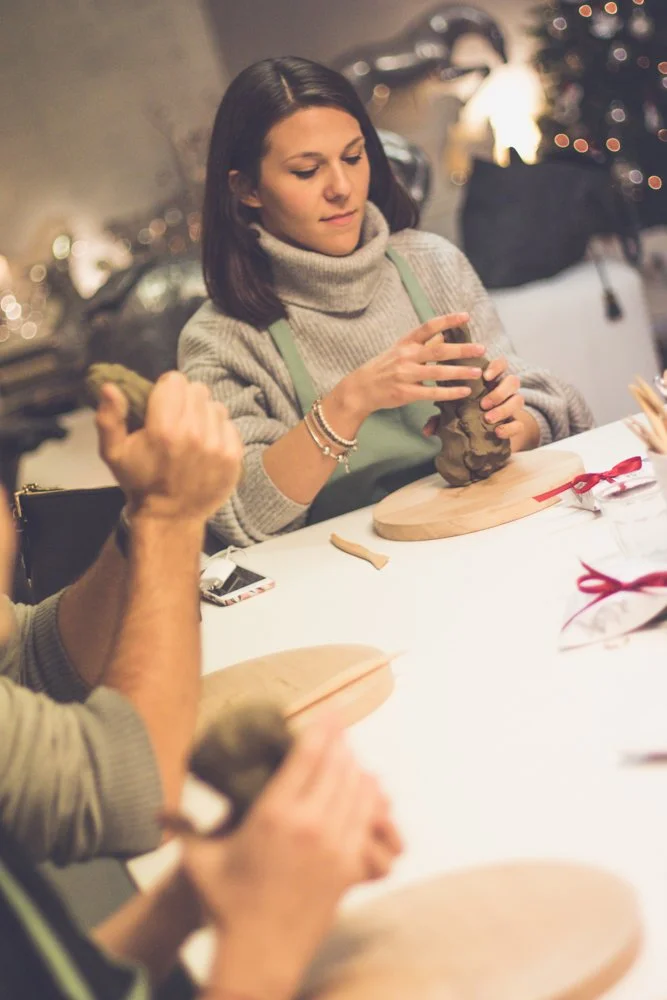 Woman sculpting with clay at a holiday gathering.