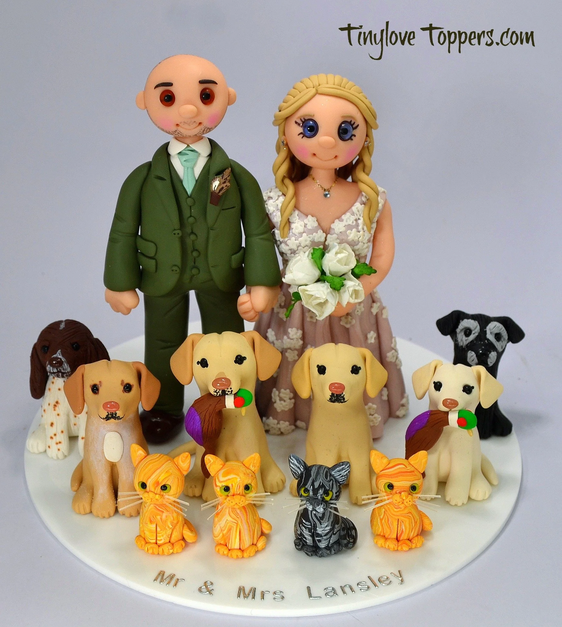 Bride and groom wedding cake topper figures standing with all their pets sat in front of them which include 6 dogs and 4 cats made by Tinylove wedding cake toppers UK