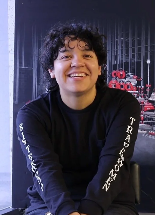 Light skinned woman with short curly hair in long sleeved black t-shirt, smiling