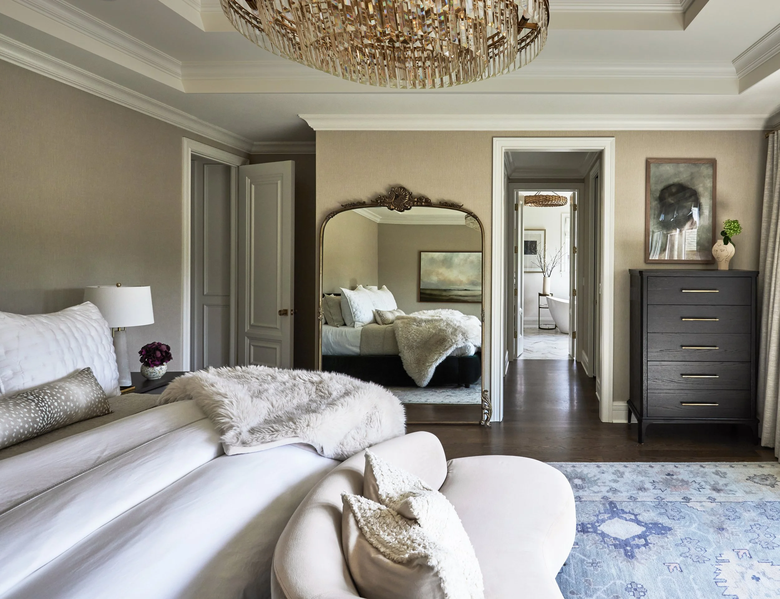 Master bedroom with crystal chandelier and chaise lounge and large brass floor mirror designed by Tracy Kurc