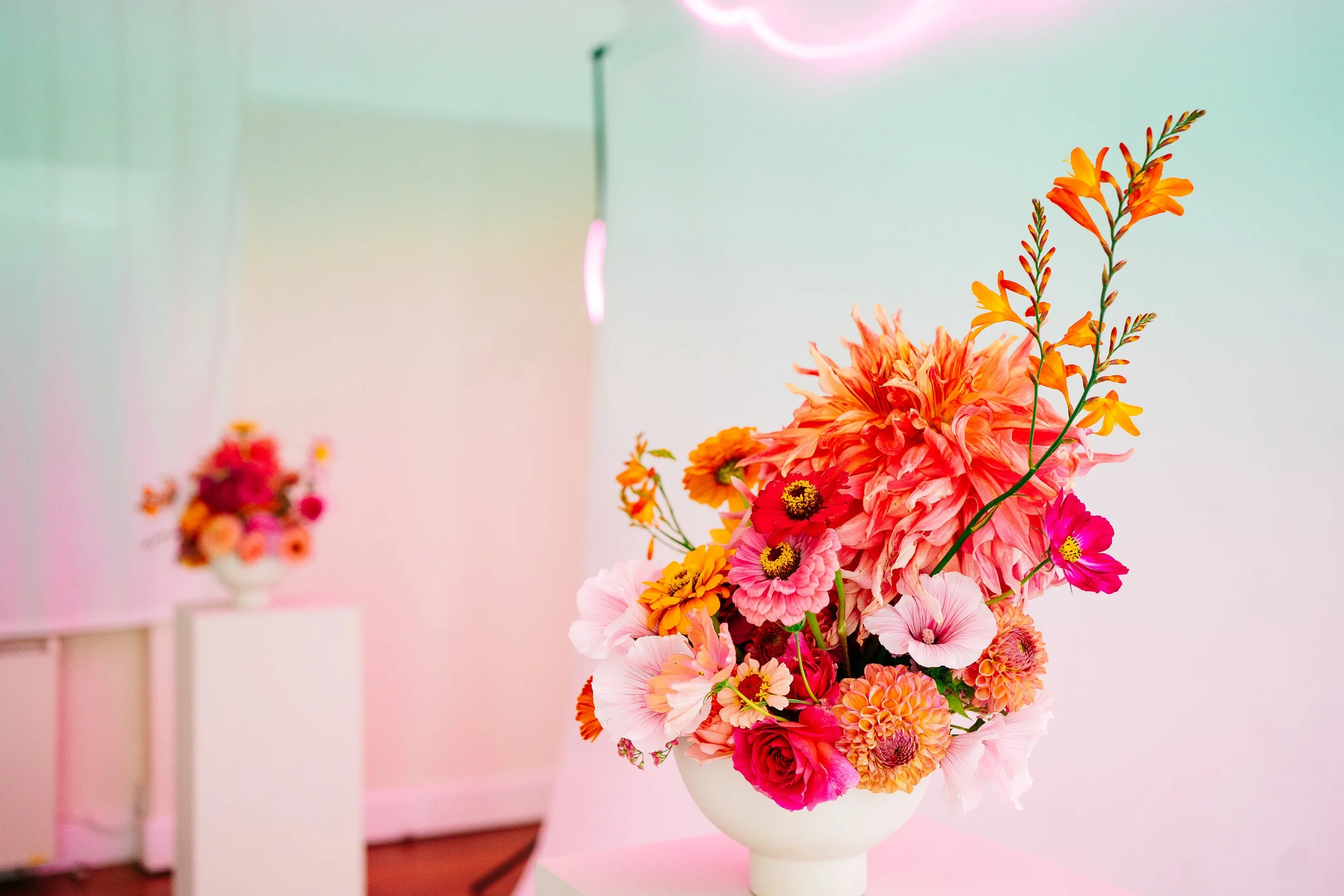 Colourful flower bowl arrangements on plinths for wedding ceremony