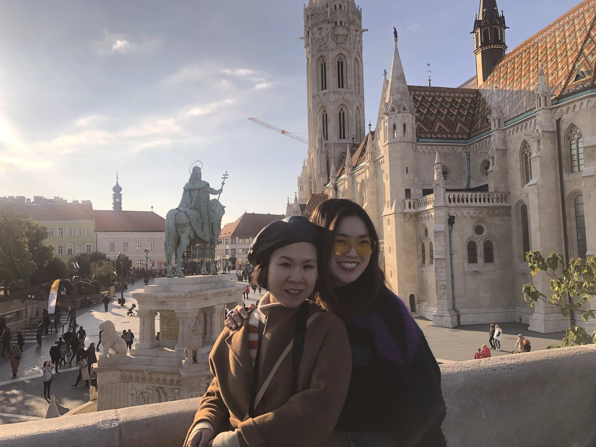 An old photo of Alice Kwan and her best friend wearing winter jumpers in front of the Buda Castle during a cold February girls' trip.