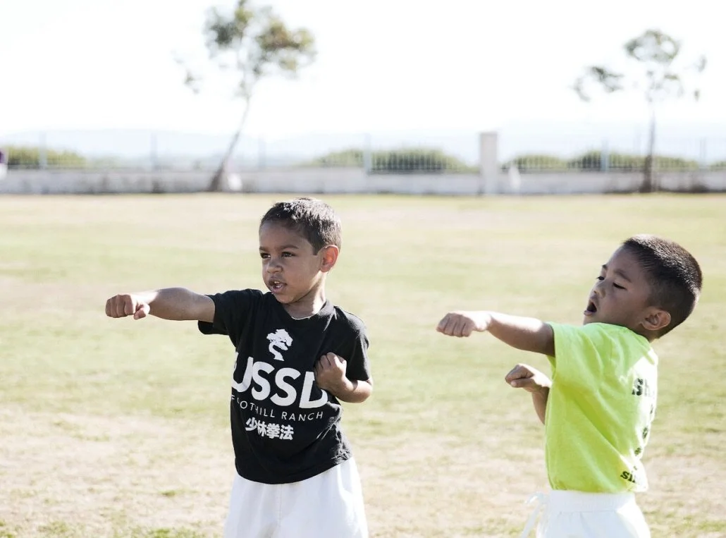 Two young boys practice their karate punches during an outdoor karate class at United Studios of Self Defense Belmont