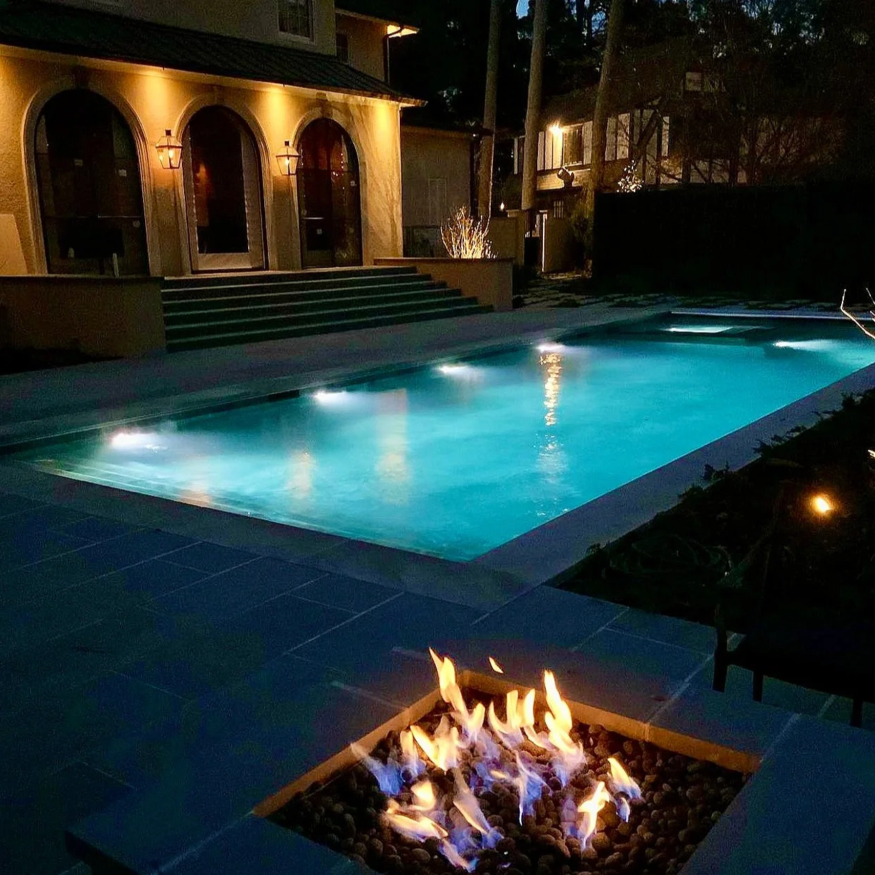 Night photo of swimming pool, spa and fire pit engineered and constructed by Waterscapes of Shreveport, Louisiana.