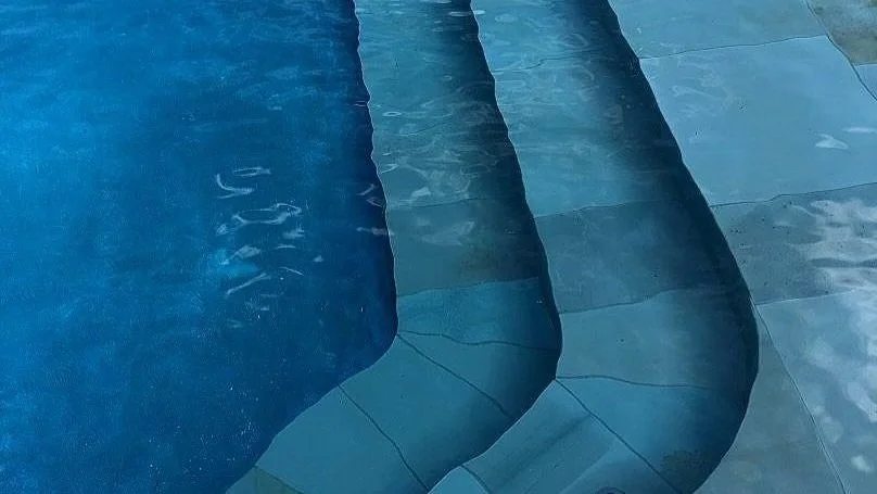 PRISTINE CRYSTAL BLUE WATER AND FLAGSTONE SWIMMING POOL STEPS DESIGNED AND CONSTRUCTED BY WATERSCAPES OF SHREVEPORT.
