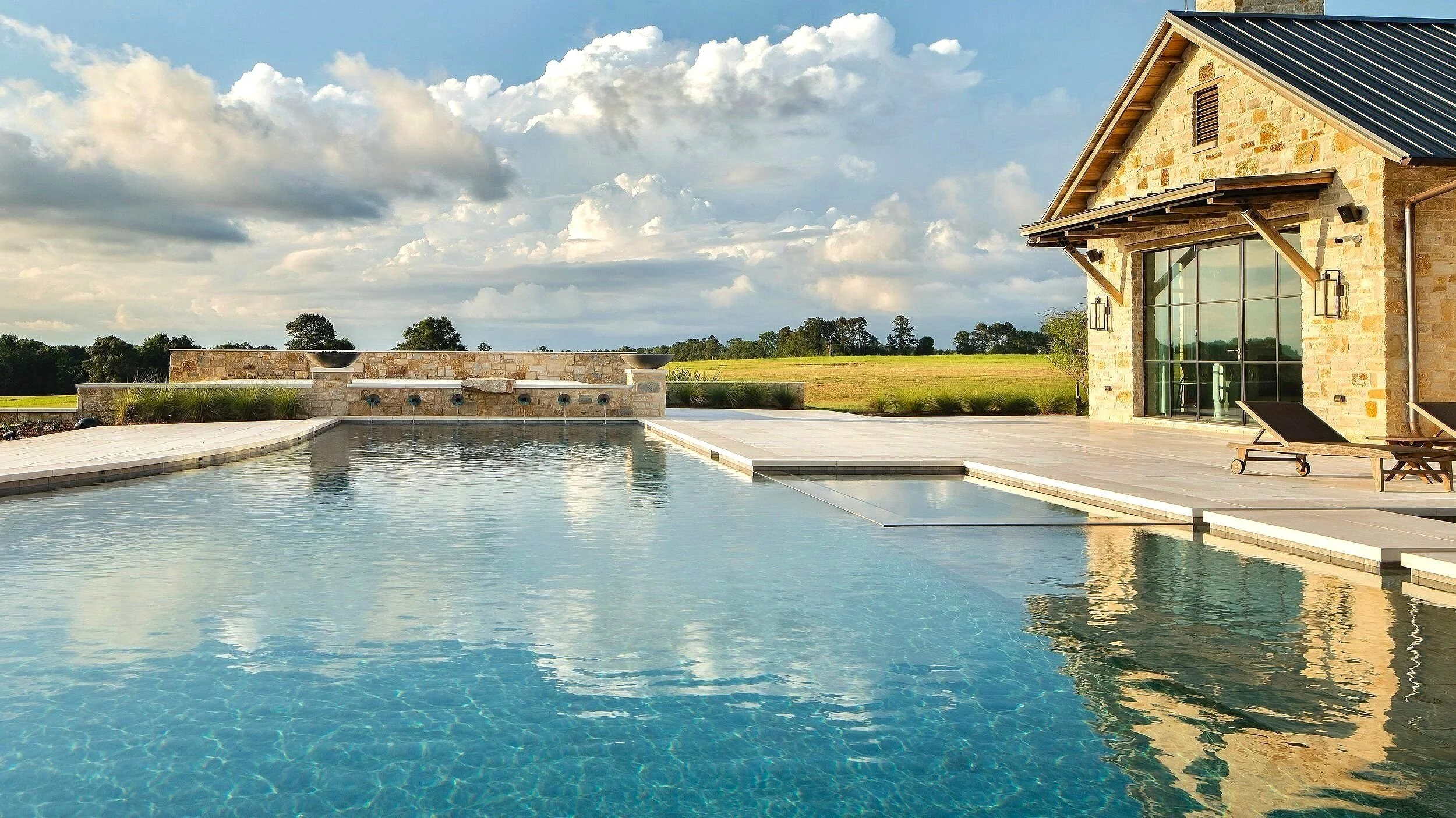 Luxury ranch home designed by Farmer Payne Architects in the piney woods of East Texas is the stunning setting for this rustic, yet elegant swimming pool, spa, and water feature engineered and constructed by Waterscapes of Shreveport, Louisiana.  Res
