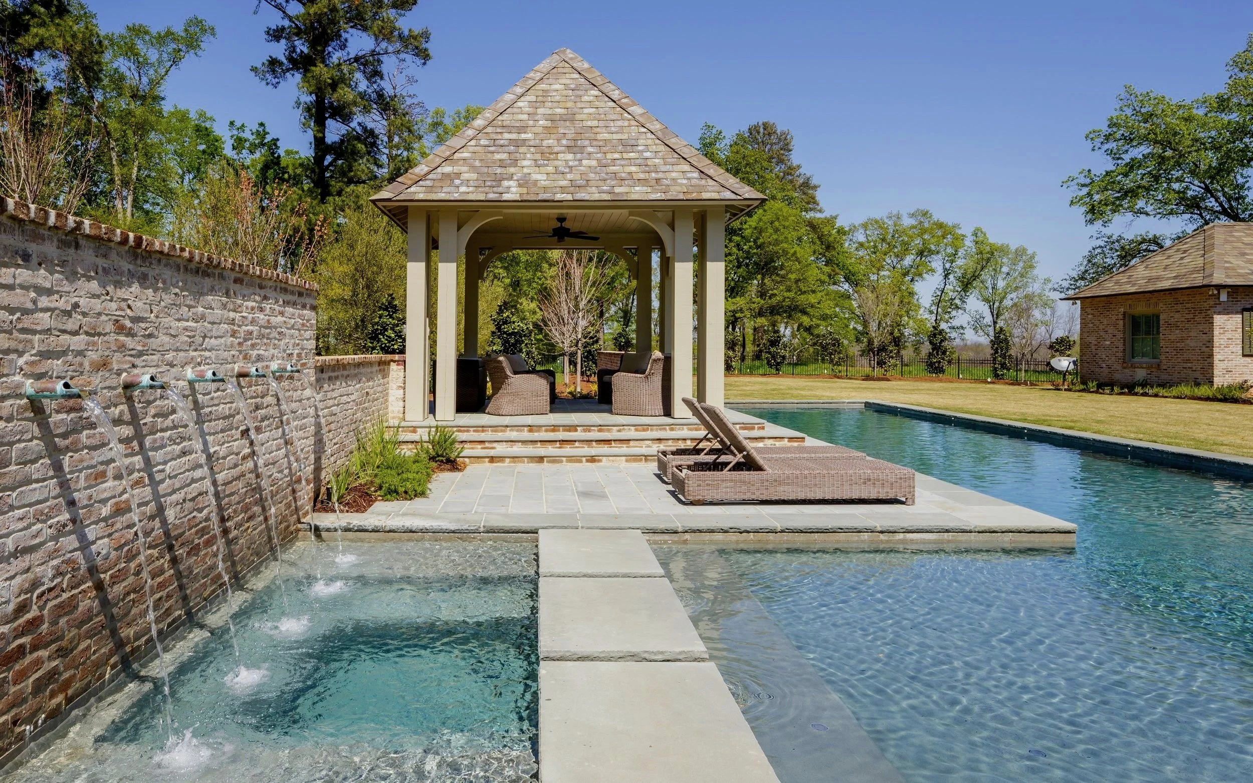 WATERSCAPES OF SHREVEPORT SWIMMING POOL AND WATER WALL FEATURING COPPER SCUPPERS THAT POUR INTO THE SPA BELOW IT.