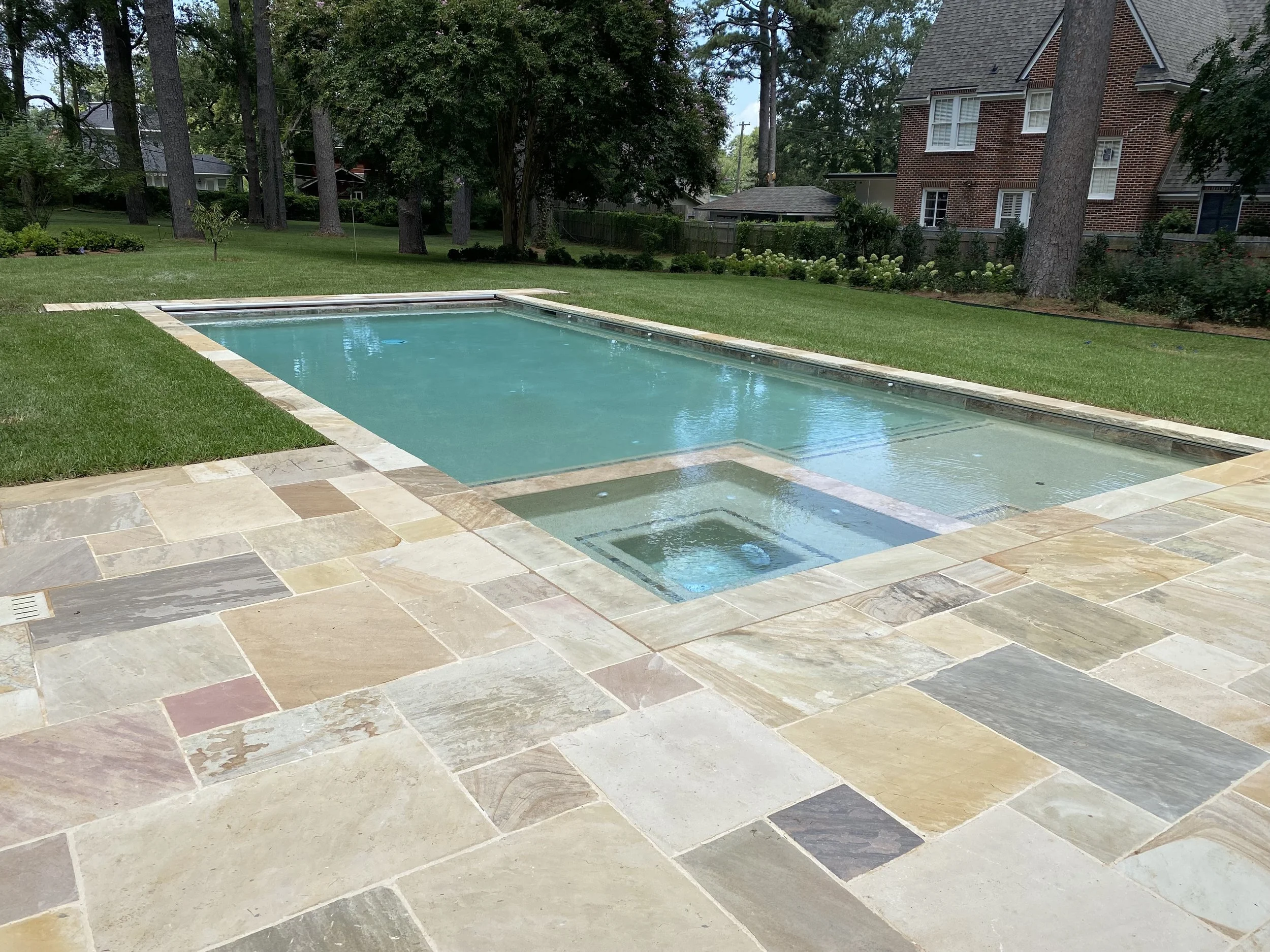 Swimming pool and spa with automatic cover designed and constructed by Waterscapes, Incorporated NWLA featuring golden flagstone and an automatic cover by Cover Pools.