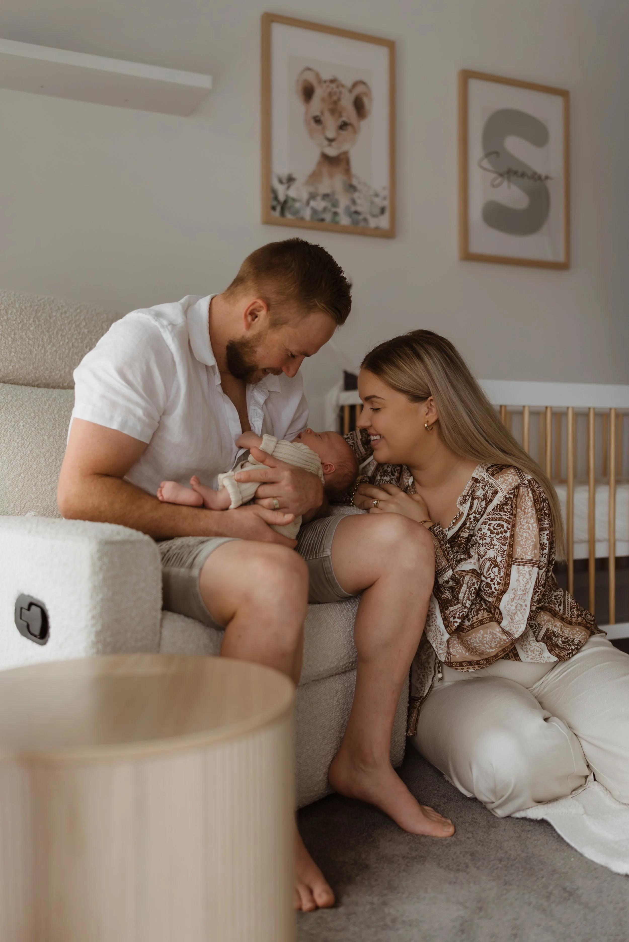 A family, father, mother, and infant, sharing a tender moment in the nursery.