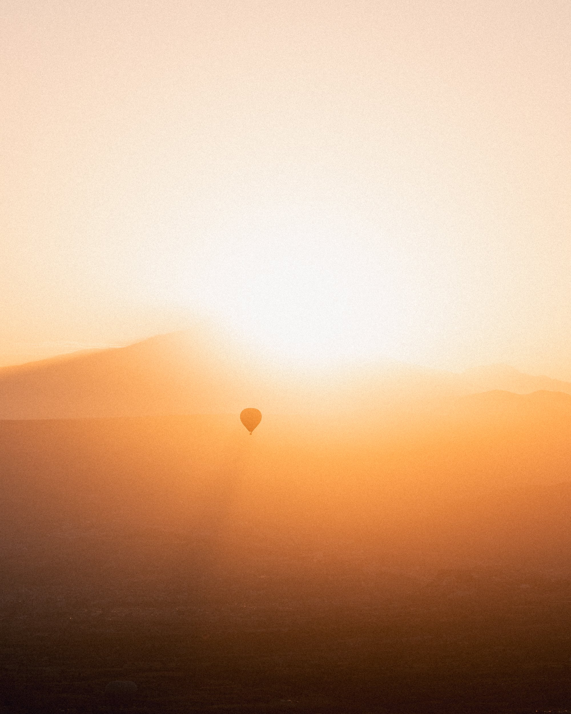 A hot air balloon in the light of a rising sun.