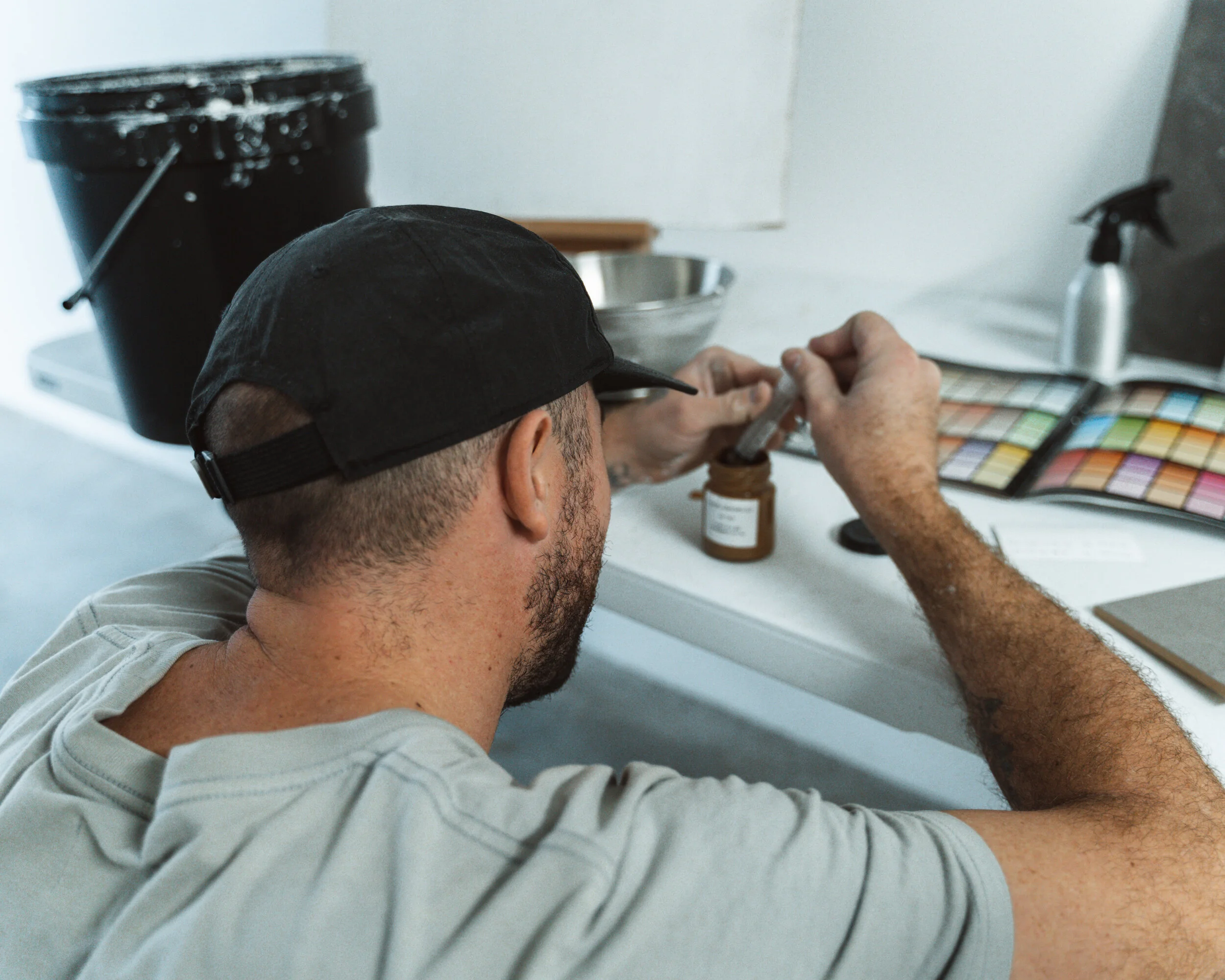 Person in a cap working with color swatches at a table.