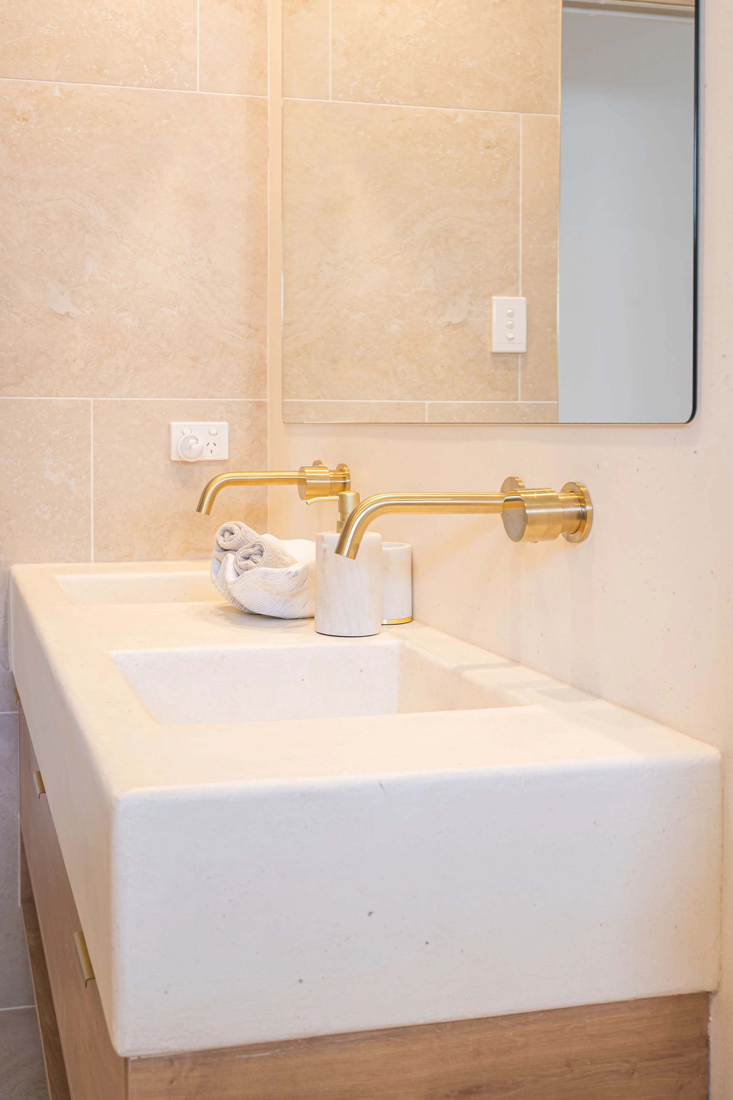 Modern bathroom sink with dual faucets, rectangular basin, and beige tiles