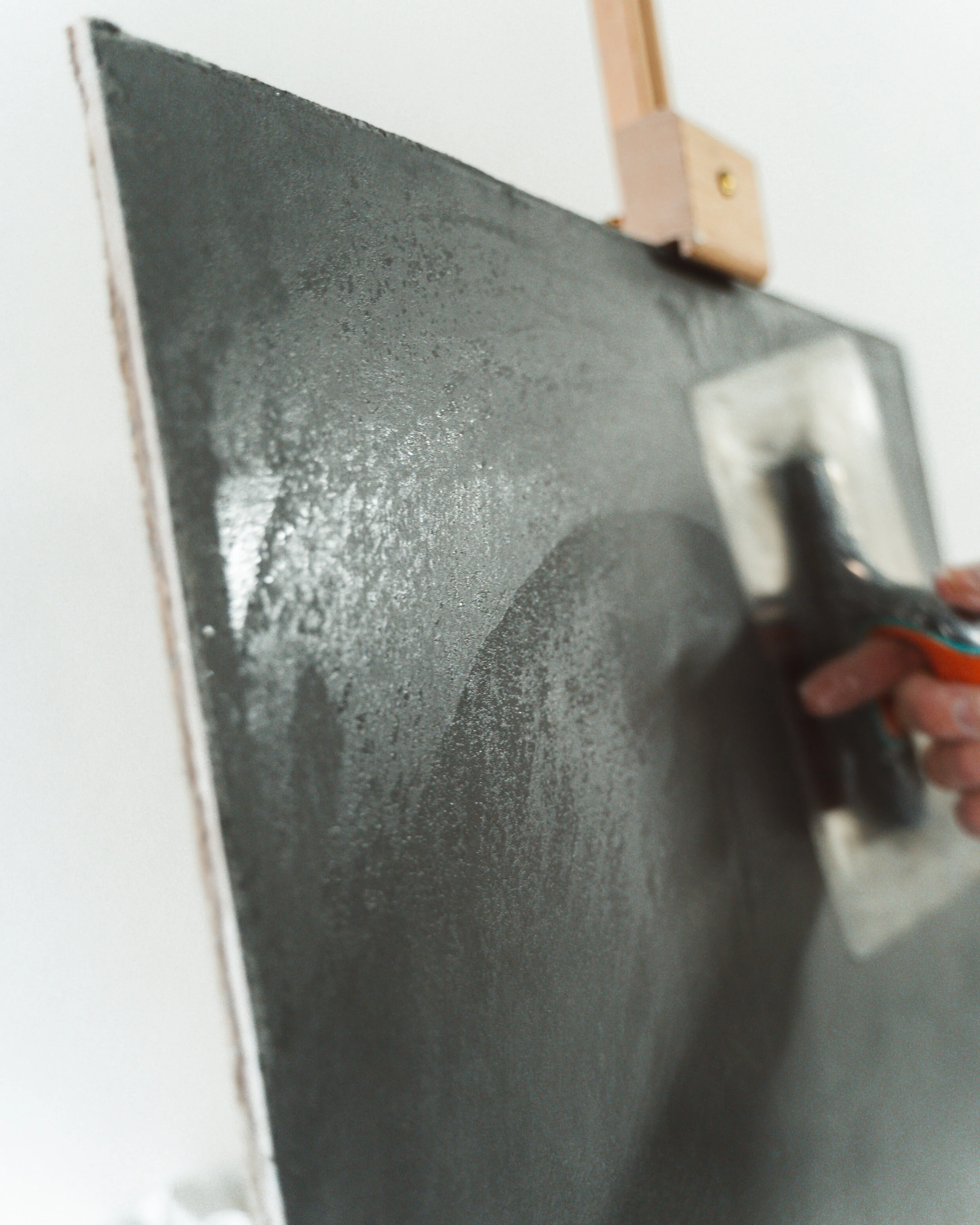 Close-up of a person using a trowel to apply plaster on a wall.