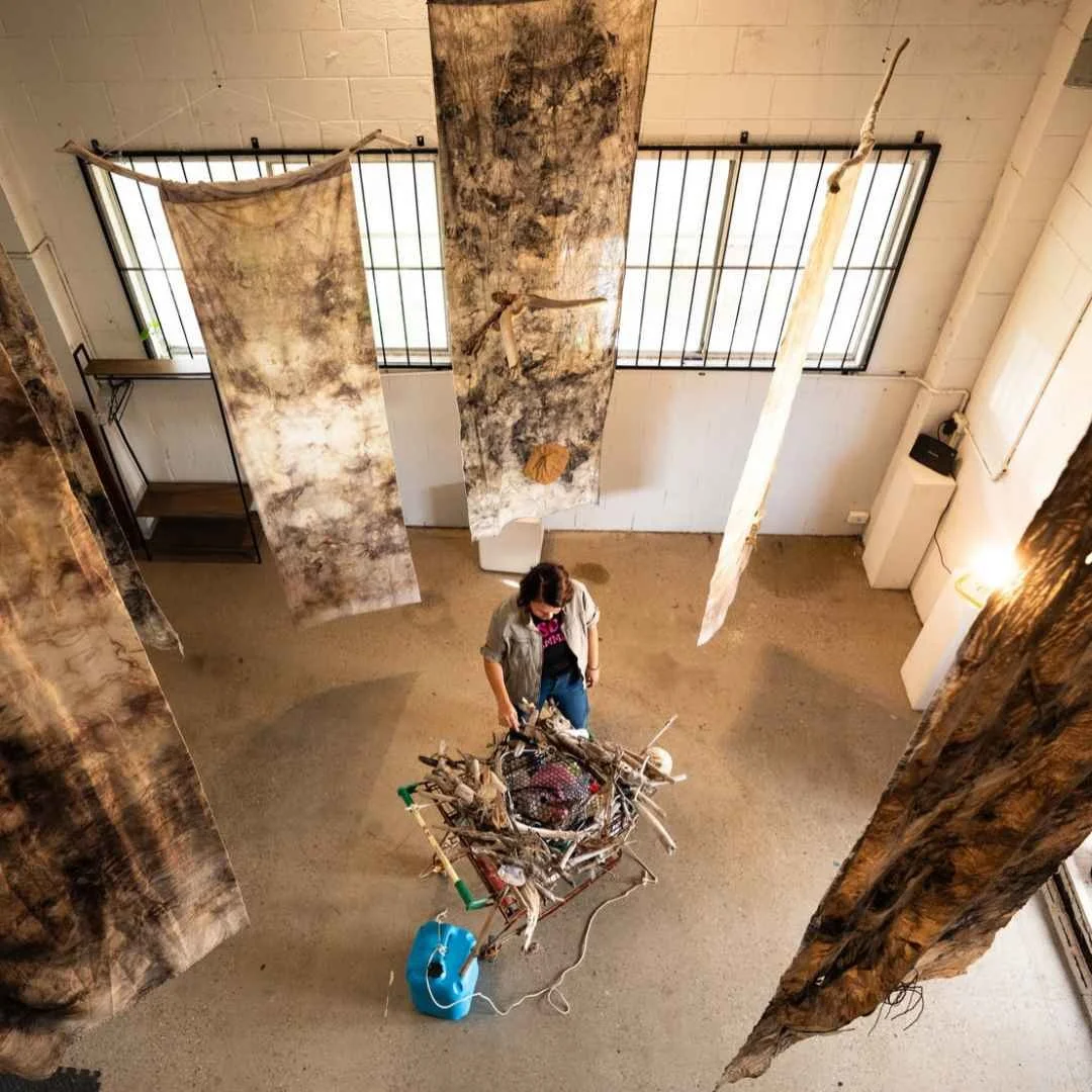 Contemporary artist Renee Mead with a sculptural installation of suspended materials in BLAKout, presented at Horizon Festival 2026 on the Sunshine Coast. Photograph by Georgia Haupt.