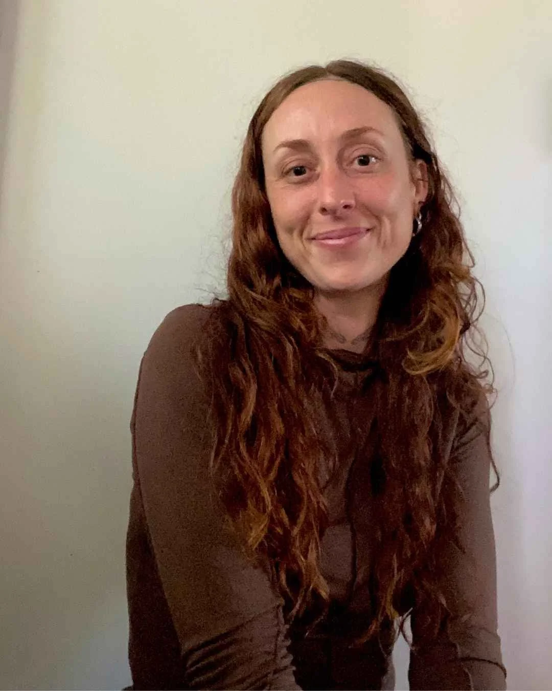 Portrait of contemporary artist Camille Therese Evans with long curly brown hair, wearing a brown top against a neutral background. LANTANA Space Artist Residency Program 2026/27.