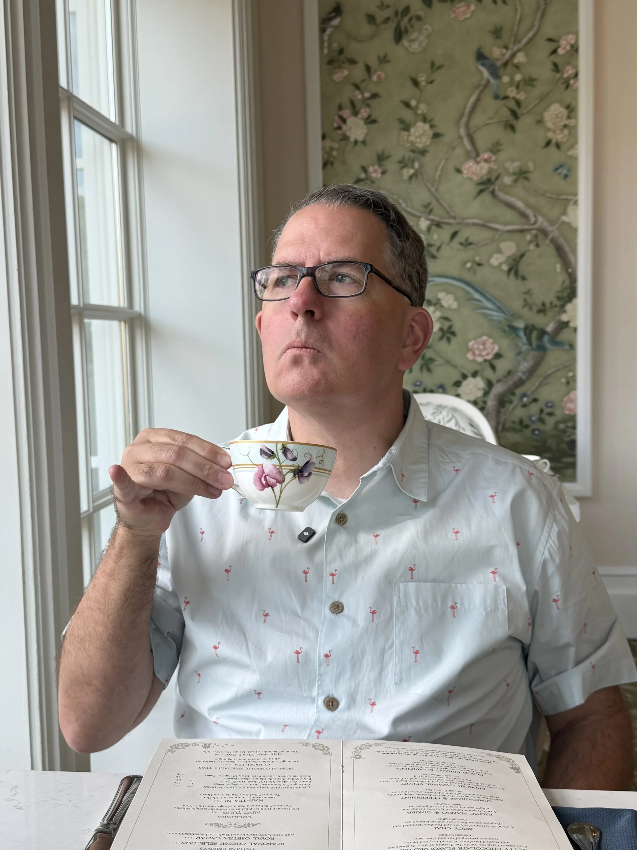 Man holding a cup of tea with his pinky out at The Garden View Lounge