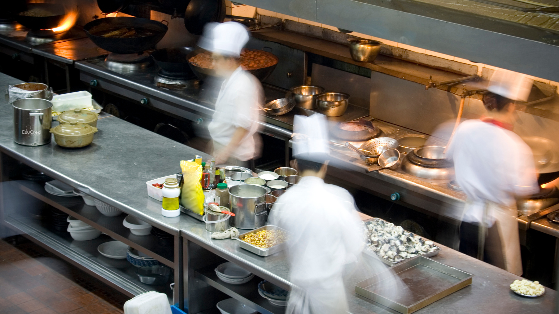Chefs moving quickly around a busy restaurant kitchen