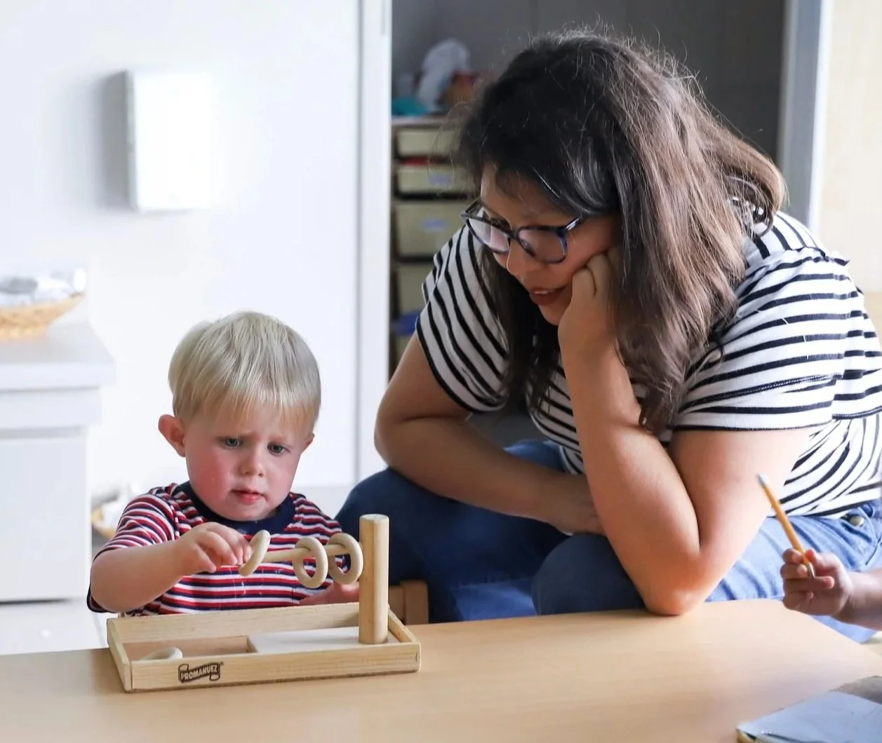 Toddler teacher watching student work with aMontessori material