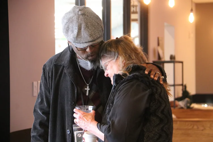 A man with his arm around a woman, praying with her at church