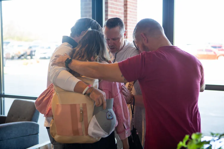 A small group gathered around a person, praying together