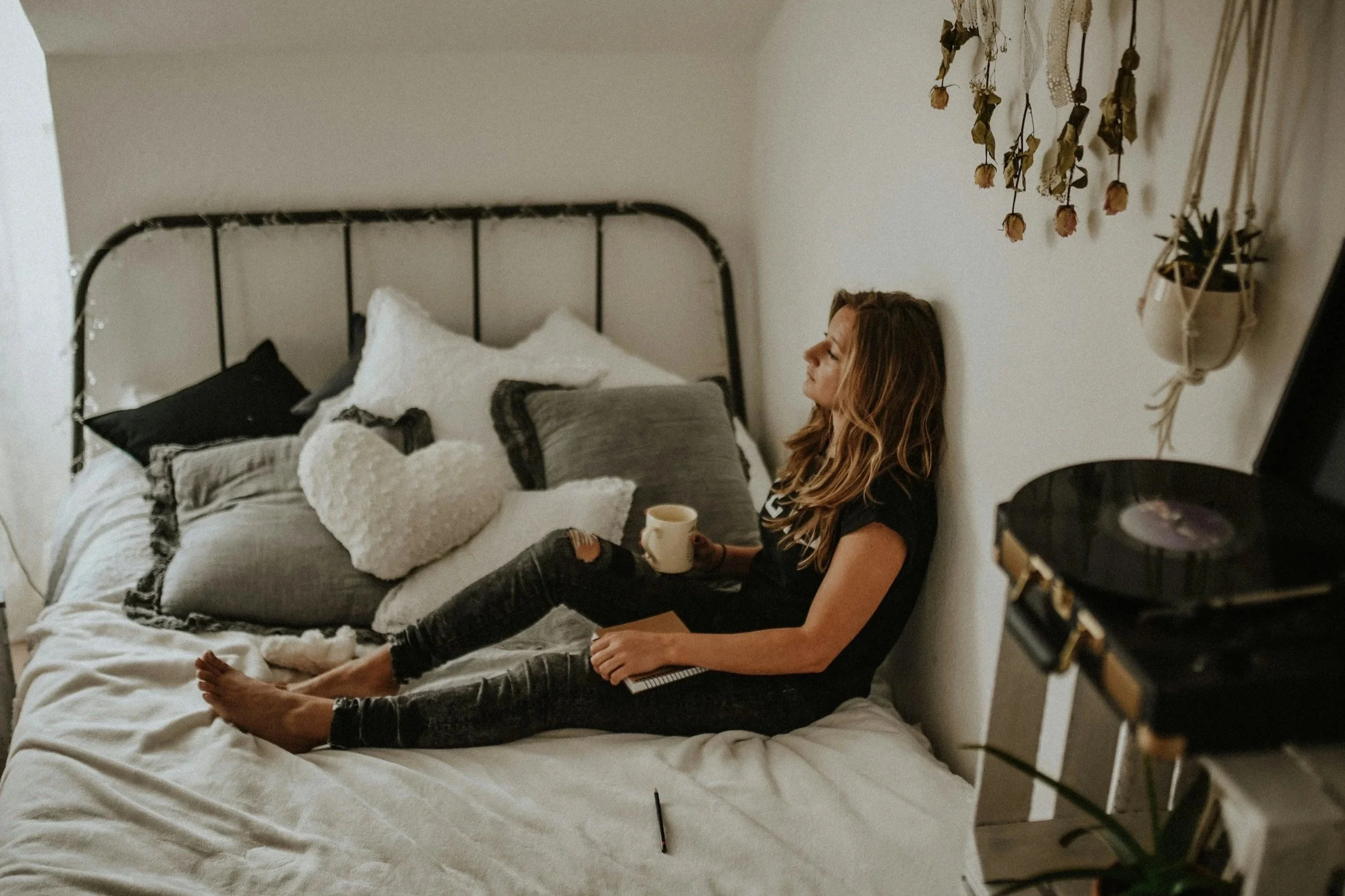 Woman sitting on her bed with coffee looking sad and depressed