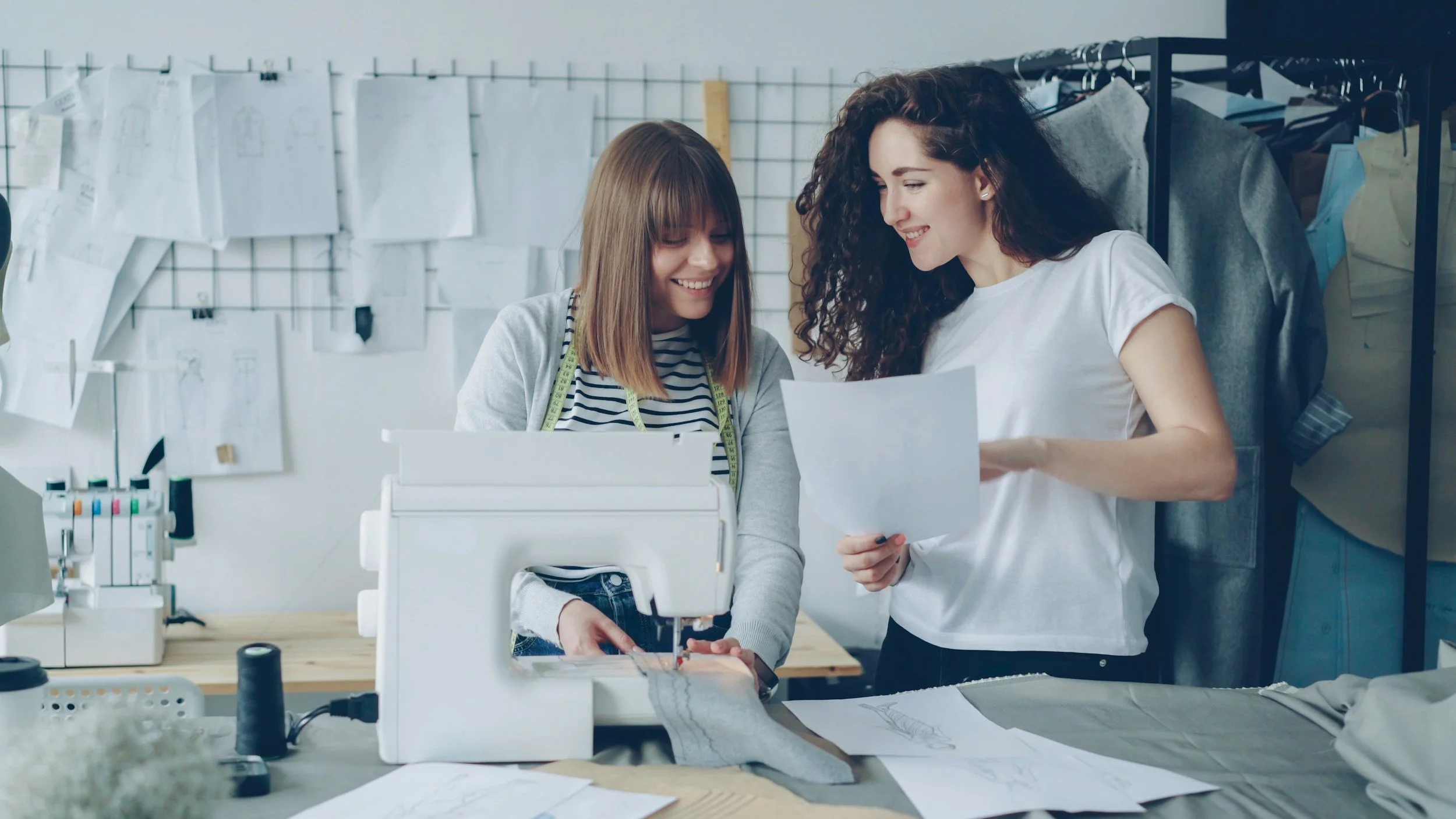 Smiling woman sewing and designing clothes with a friend