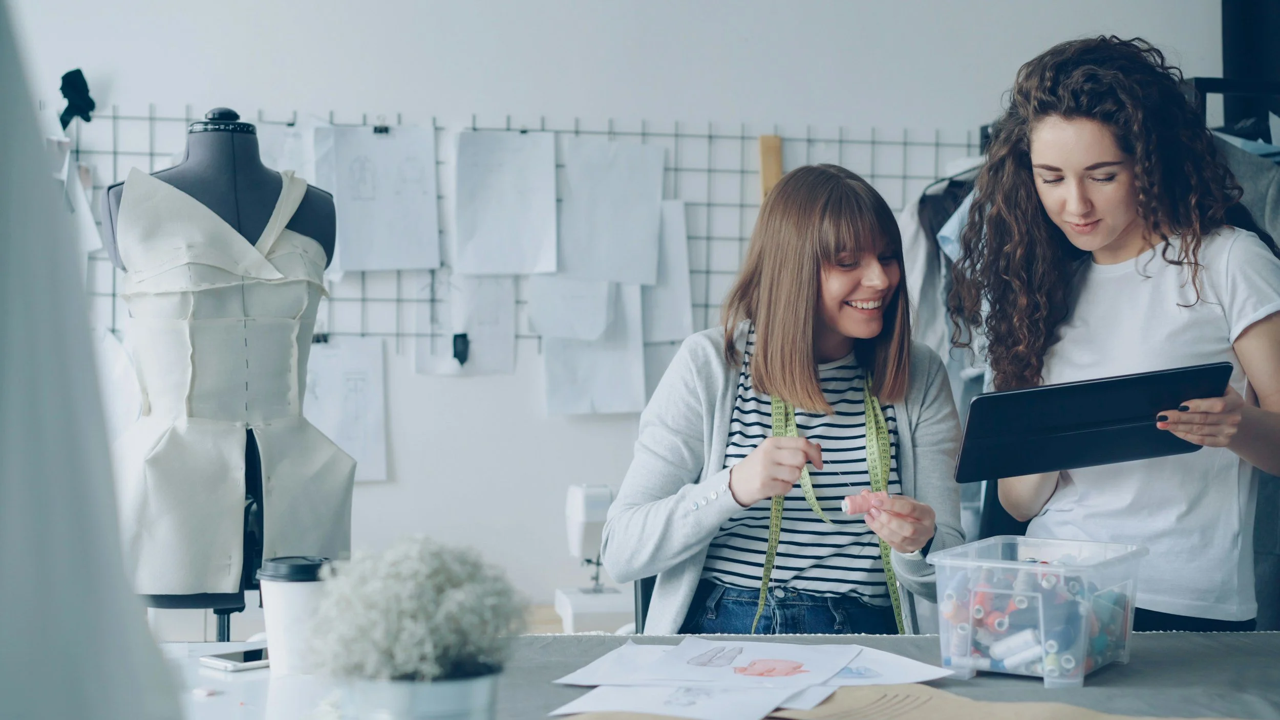 Two women designing and sewing clothes in a studio