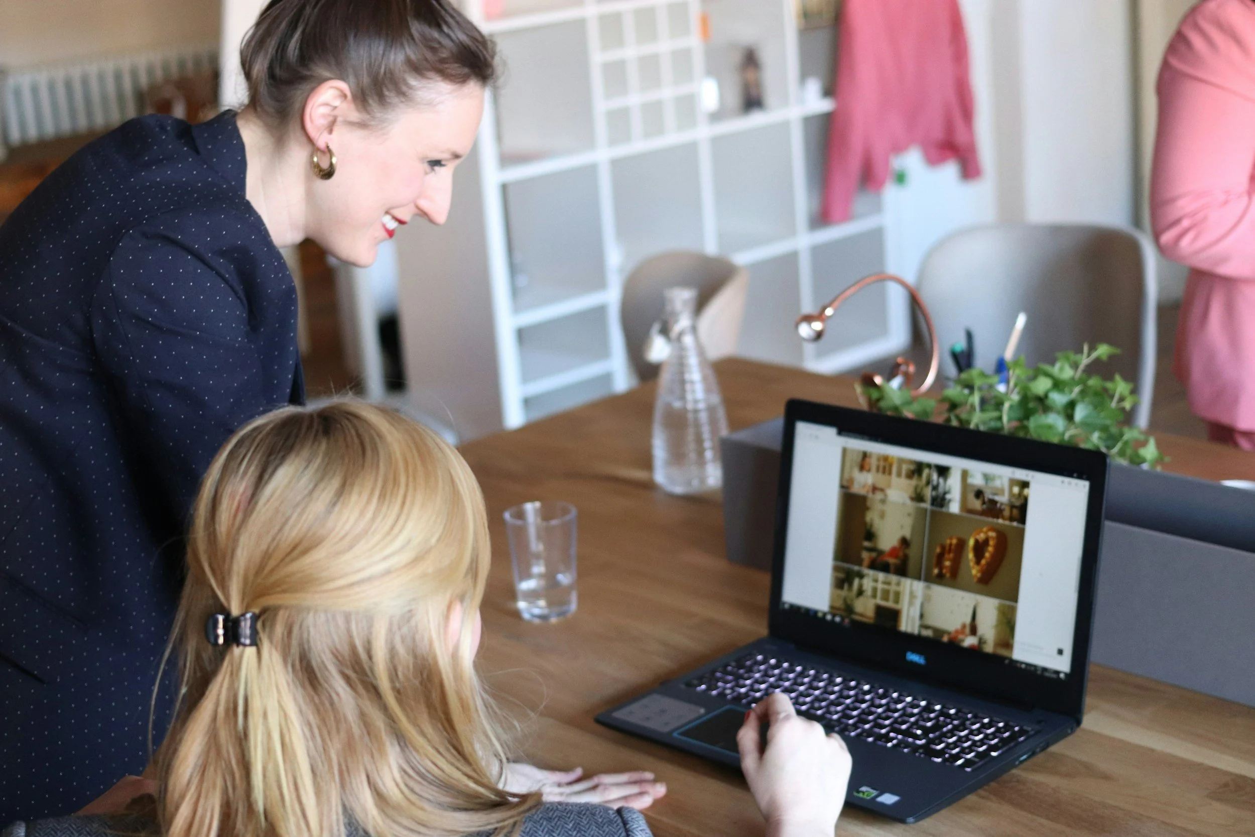 Two women smiling looking at a laptop of pictures together