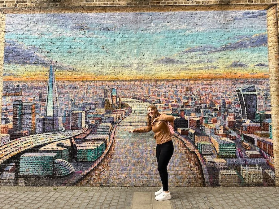 Suzie DeVoe posing with a wall mural of the city in South Bank, London