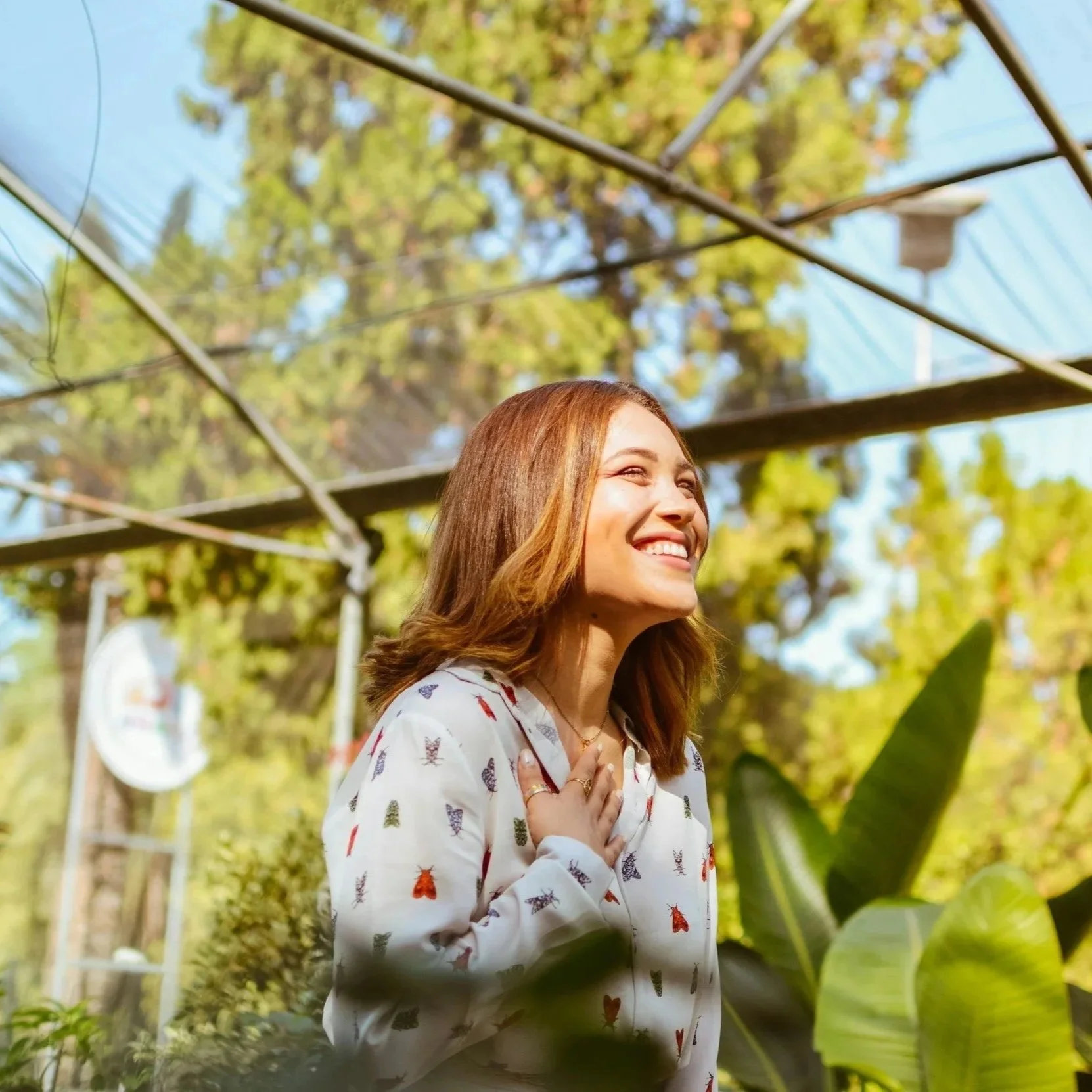 Happy woman smiling with a hand on her heart in a greenhouse with plants