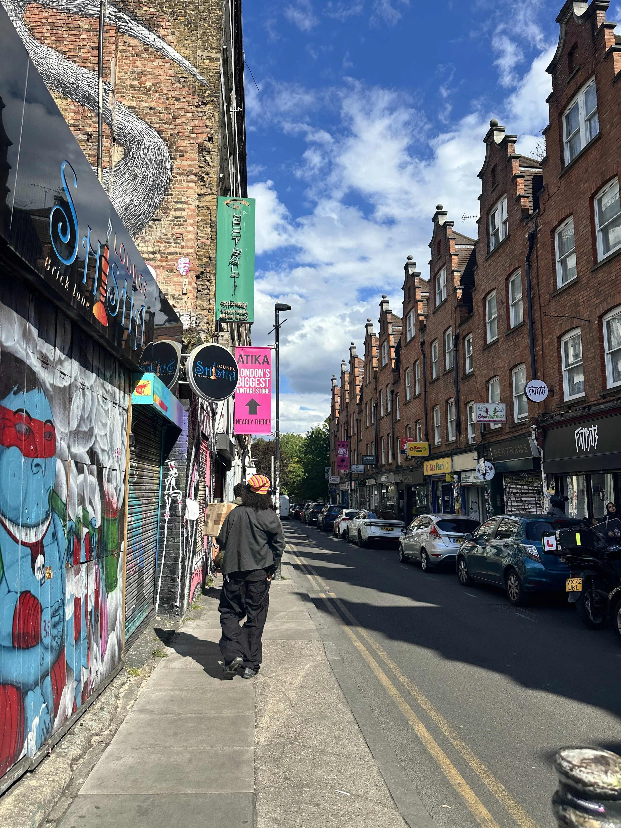 Street scene with a walking man and graffiti along Brick Lane, London