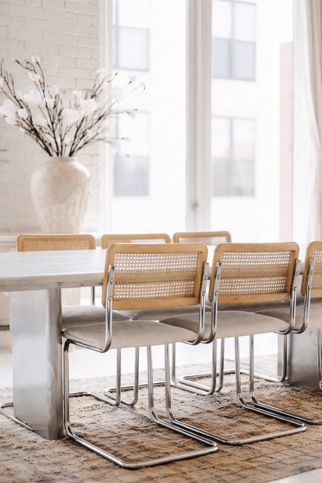 Modern dining room with cane-back chairs and floral arrangement in a private residence — My Household Managed