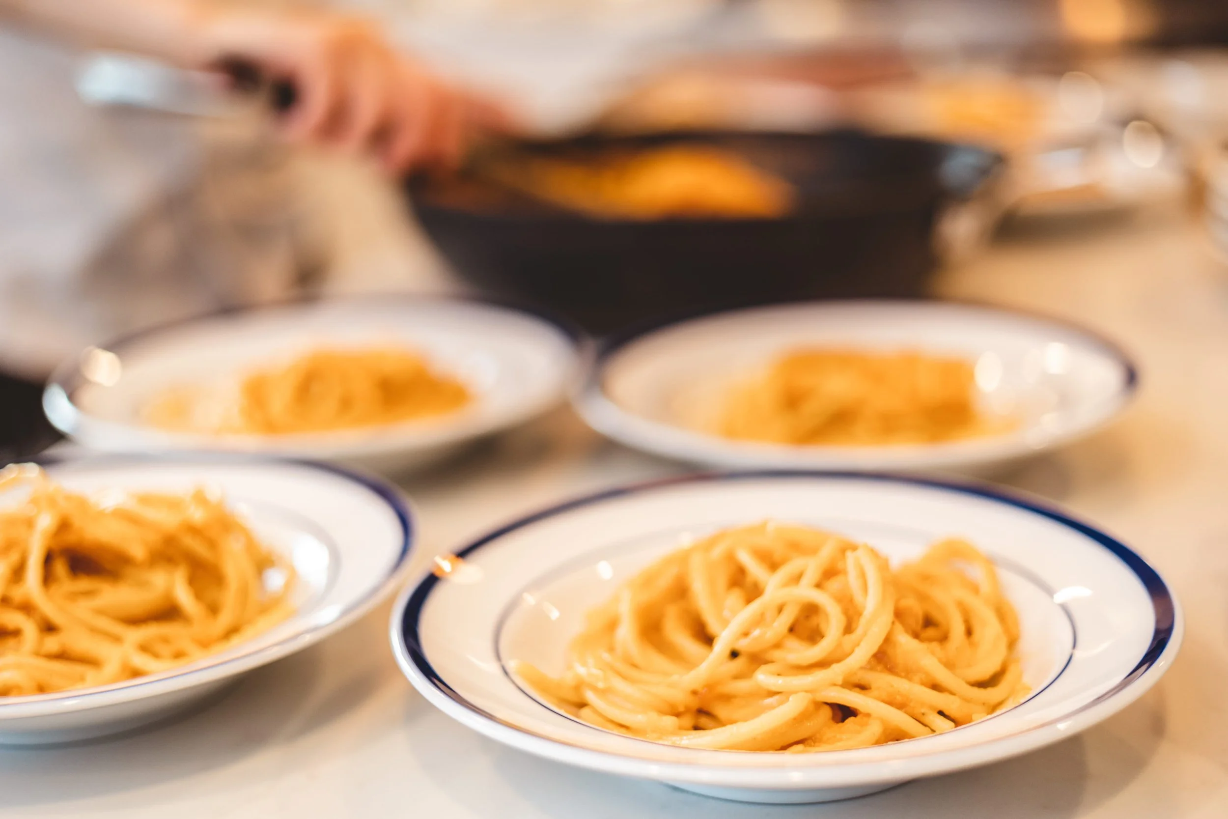 Private chef plating pasta courses for a dinner party in a Chicago luxury home kitchen.