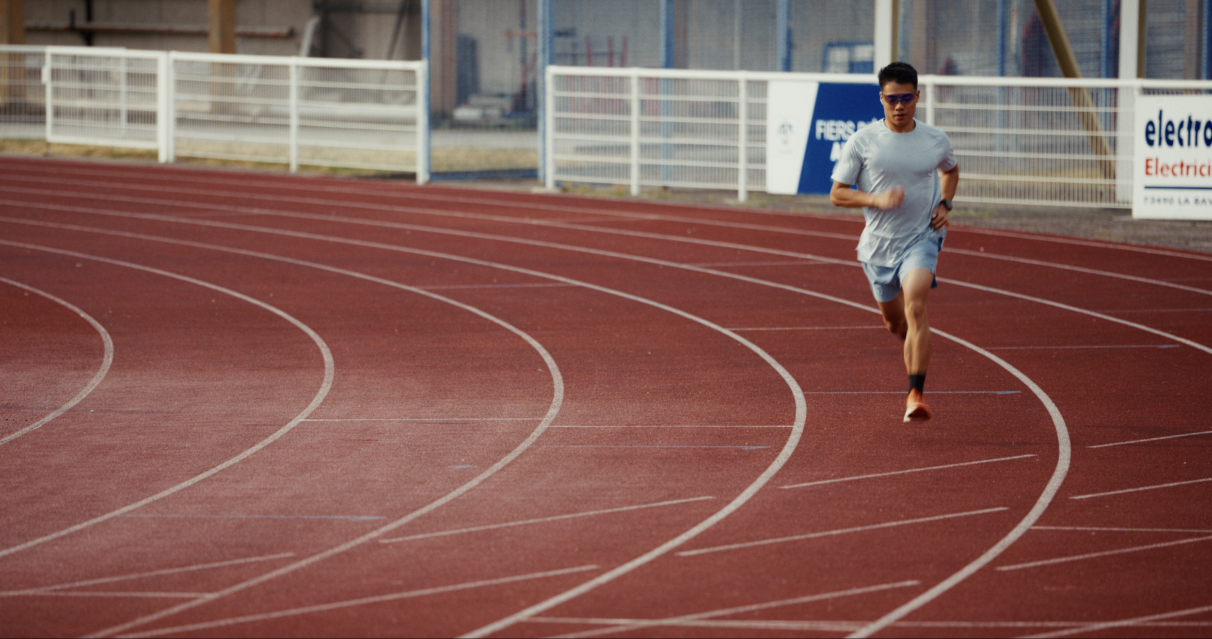 Piste d'athlétisme rouge vue du dessus, coureur en action — film sportif cinématique