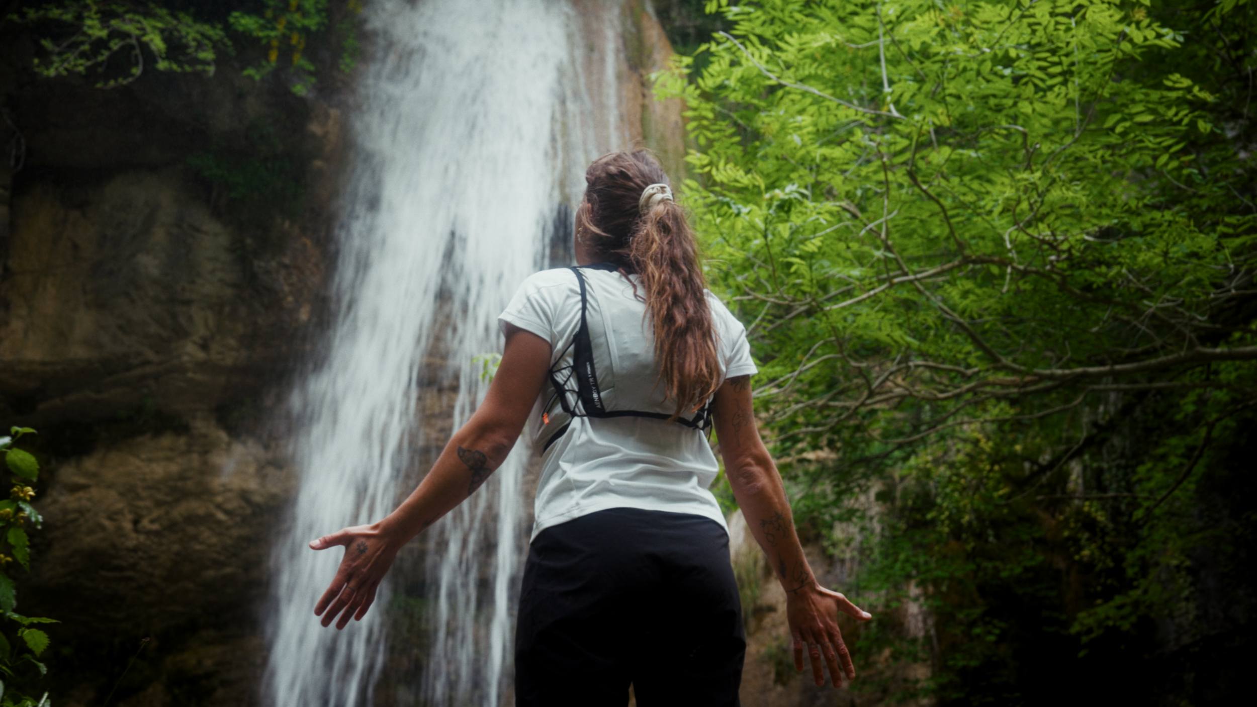 Marie Gamen face à une cascade, bras ouverts, nature et ressourcement