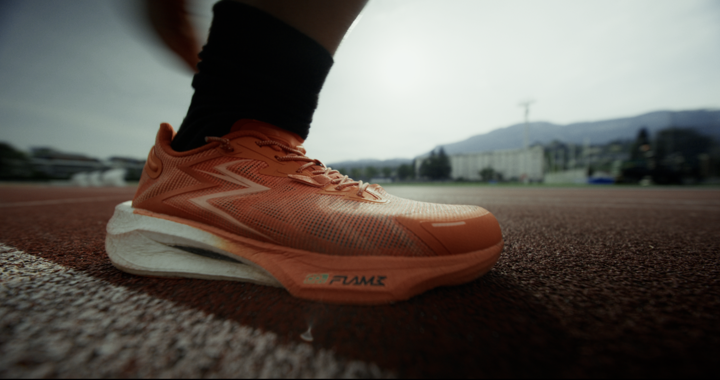 Chaussure de running orange sur bitume, gros plan cinématique