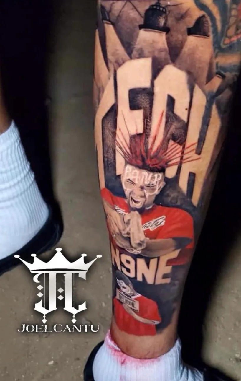 Tattoo of a man in a red shirt praying, with a large stylized word 'PEACE' or similar above his head, on his leg.