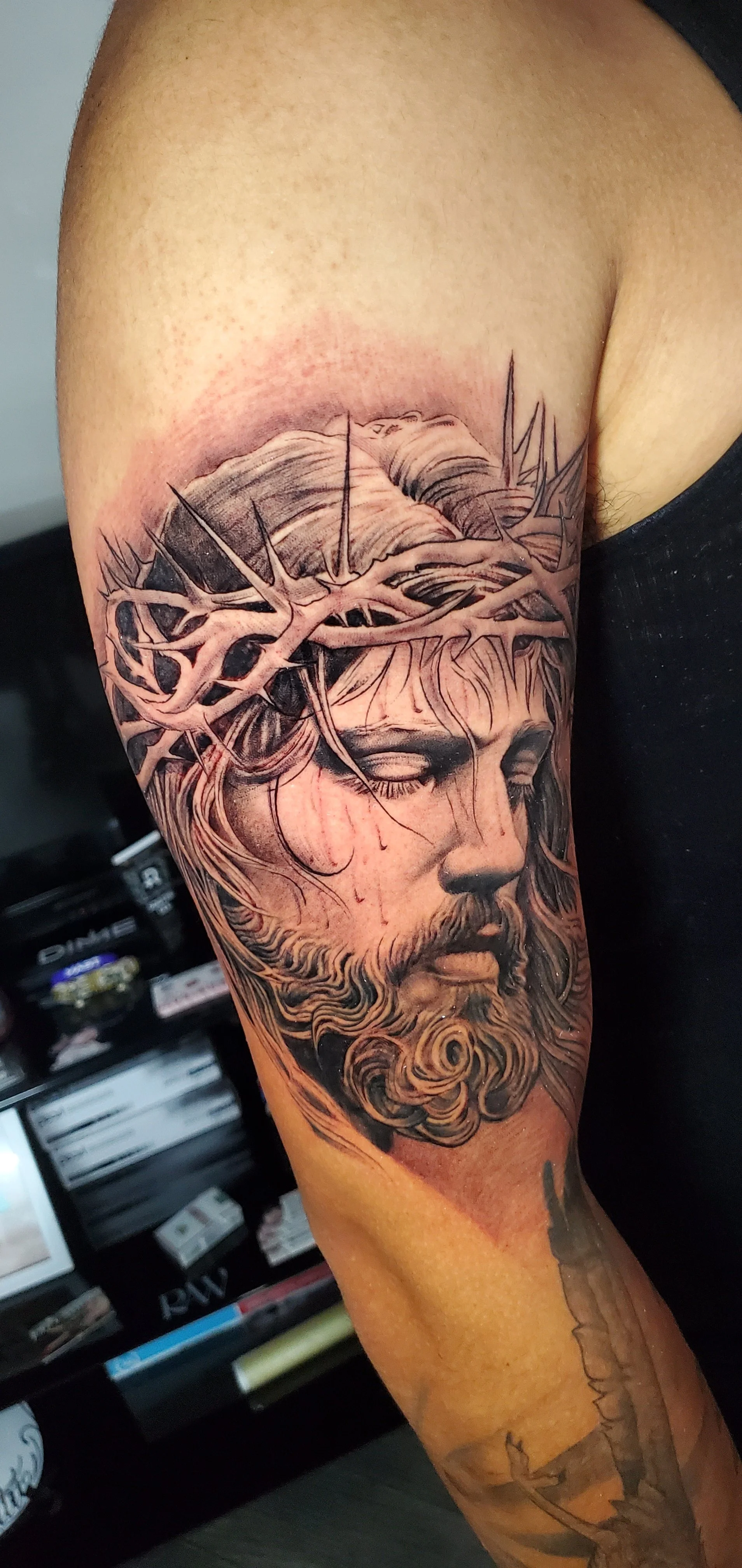 Tattoo of Jesus Christ with a crown of thorns on the upper arm.