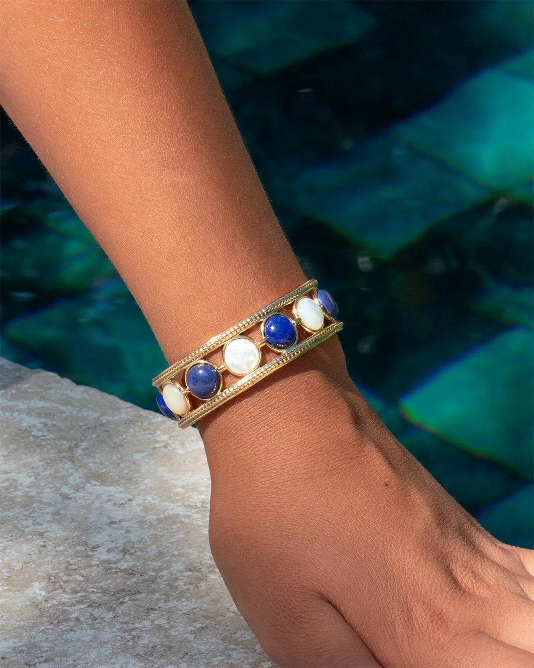 Bracelet Nefertari lapis-lazuli et nacre porté au poignet, bijou doré à l'or 18 carats d'inspiration égyptienne