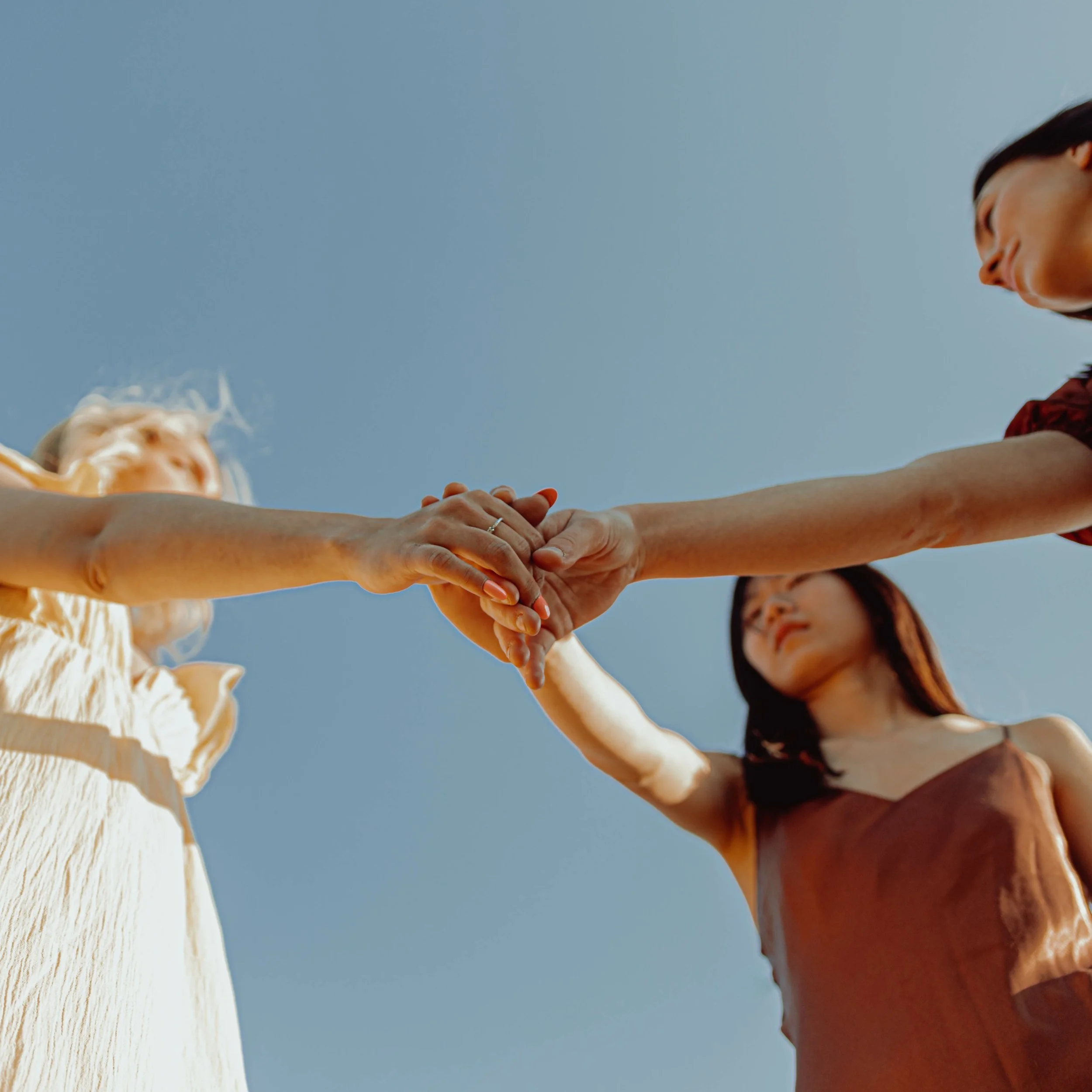 Original Soulloop campaign photograph of people joining hands beneath a blue sky