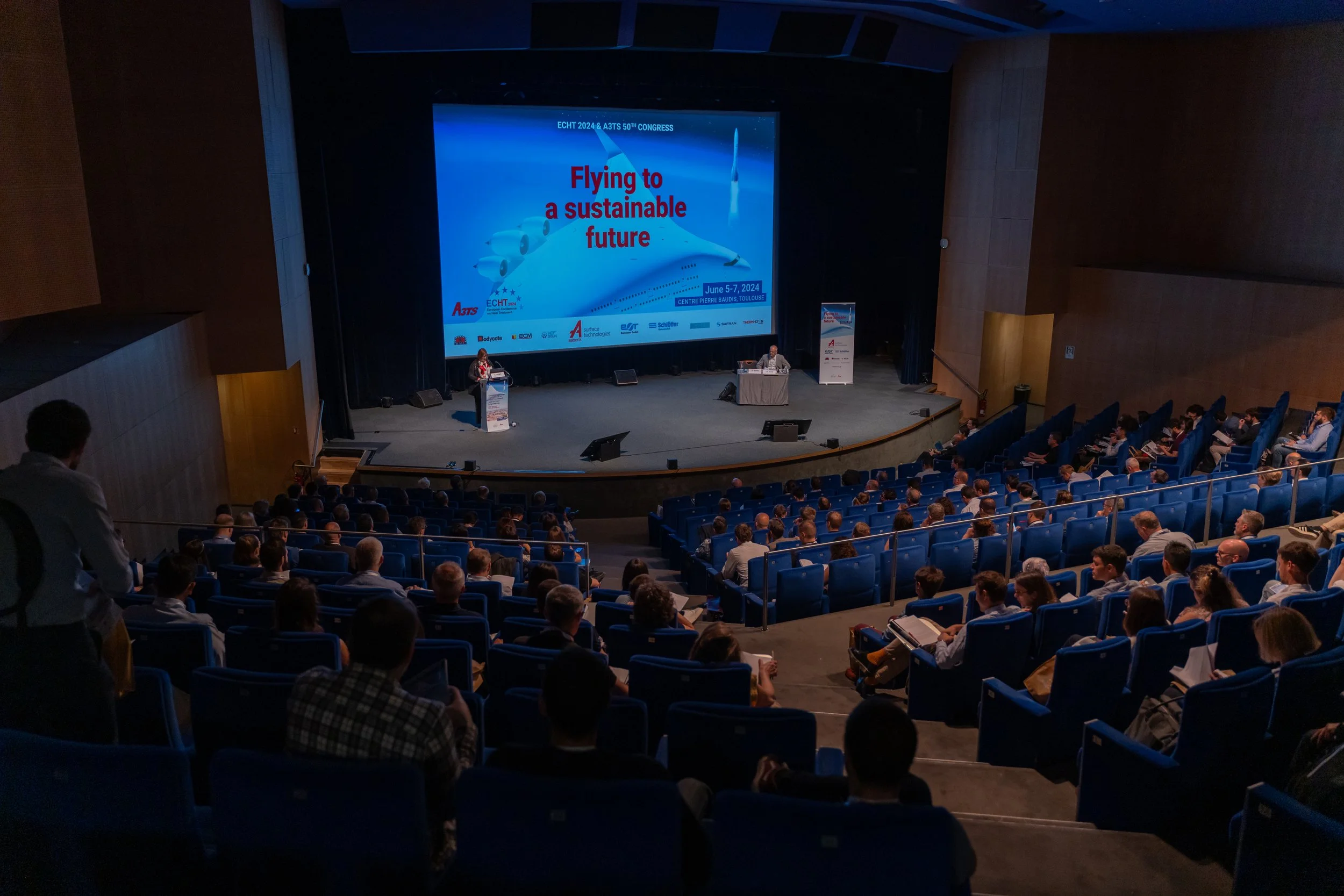 Conférence sur l'aviation durable avec auditoire et présentation "Flying to a sustainable future" sur écran.