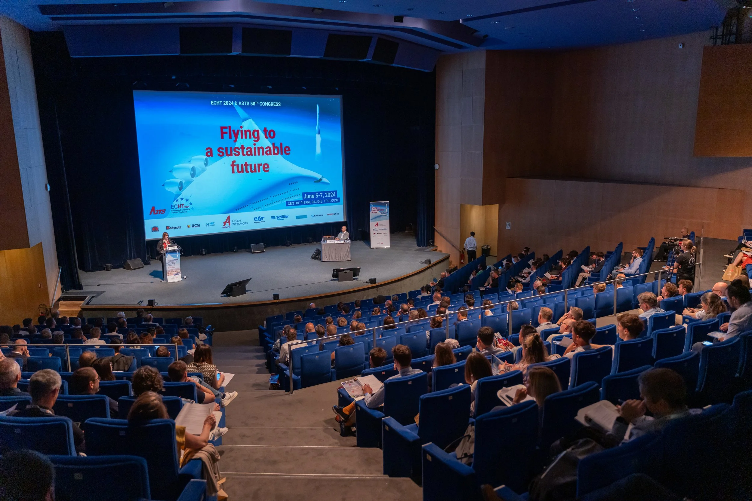 Conférence avec une présentation sur "Flying to a sustainable future" au congrès ECHT 2024 & A3TS, avec des participants assis dans un auditorium bien rempli.