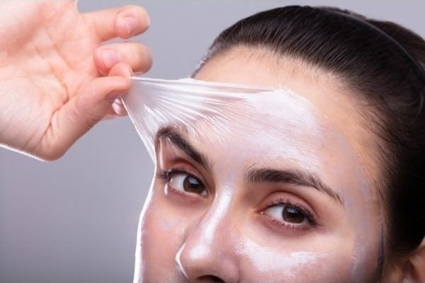 A woman pulling off peeling skin from her face.