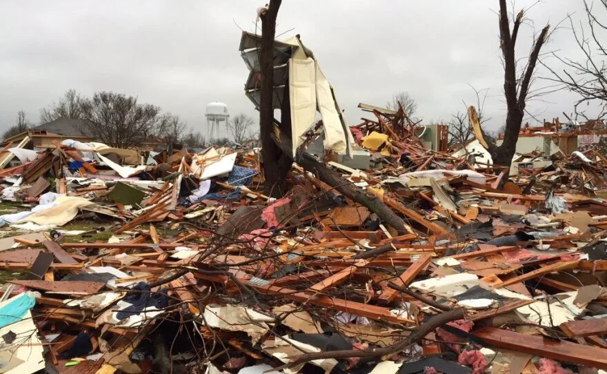 Debris and wreckage from destroyed buildings and trees in a storm or tornado aftermath.