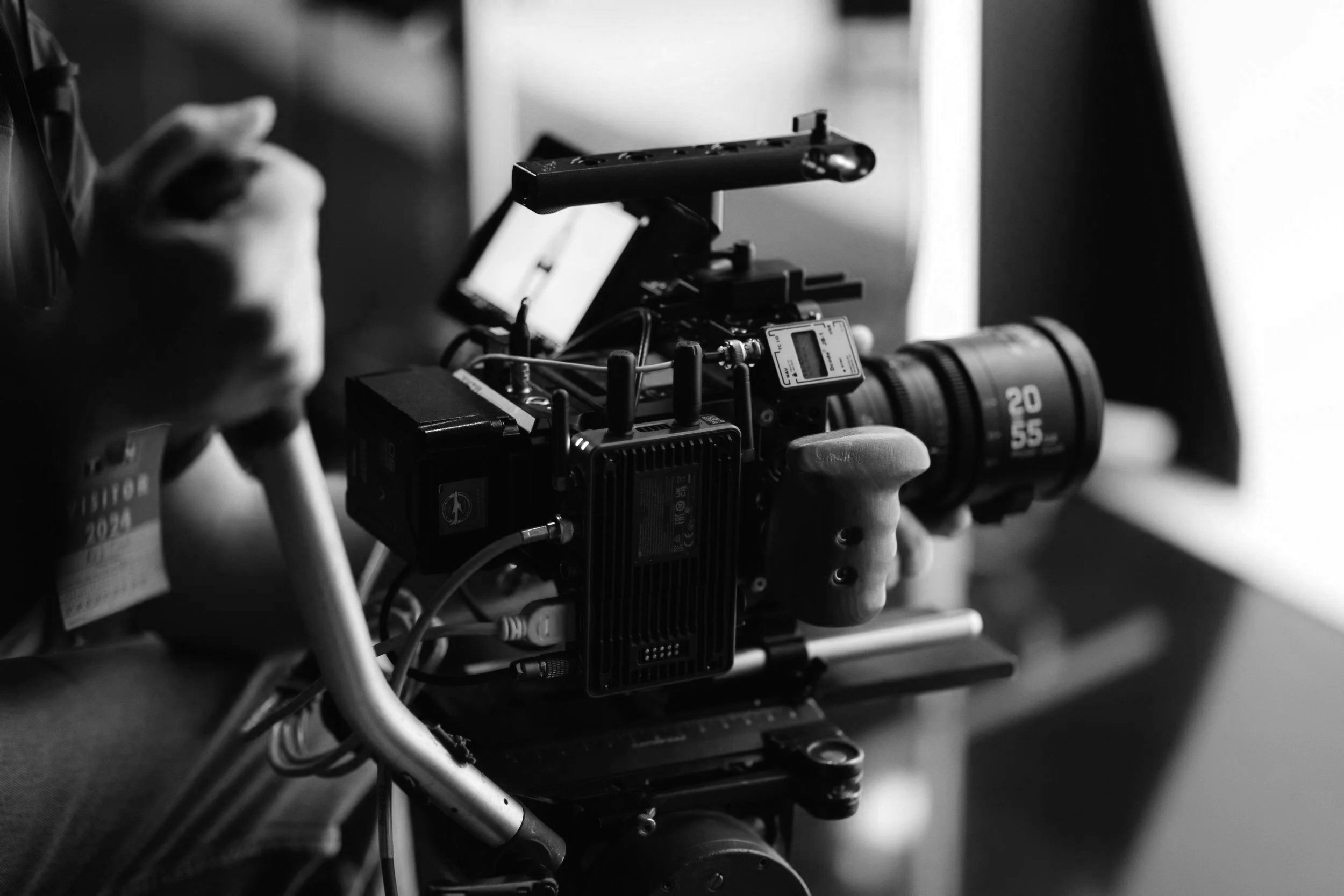 Black and white photo of a professional video camera with various cables and accessories attached.