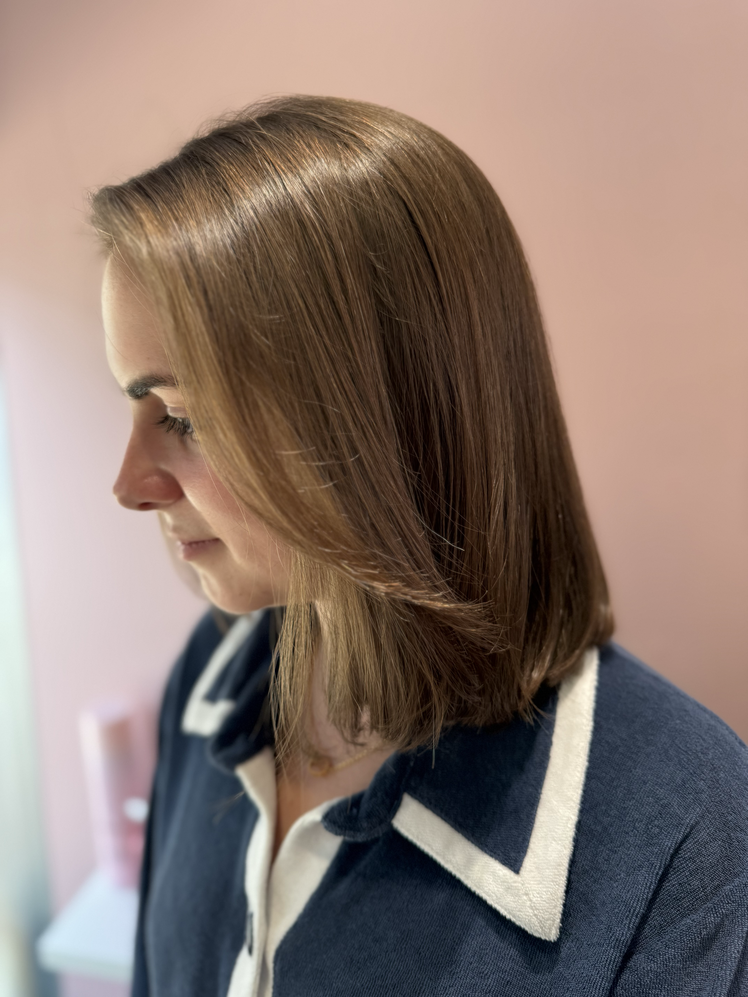 Profile of a woman with long, straight, brown hair wearing a navy blue and white striped hoodie.