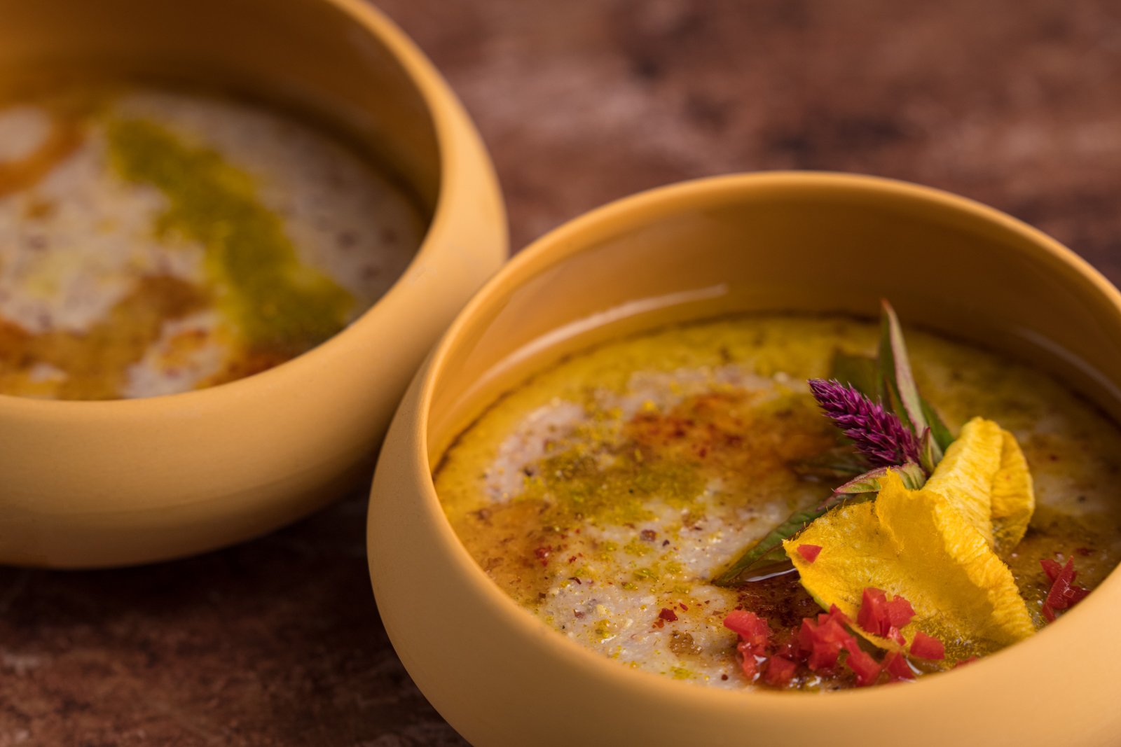 Bowl of creamy soup garnished with colorful edible flowers and spices